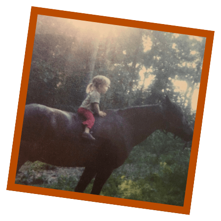 Seoka as a child sitting on a horse in a wooded setting.