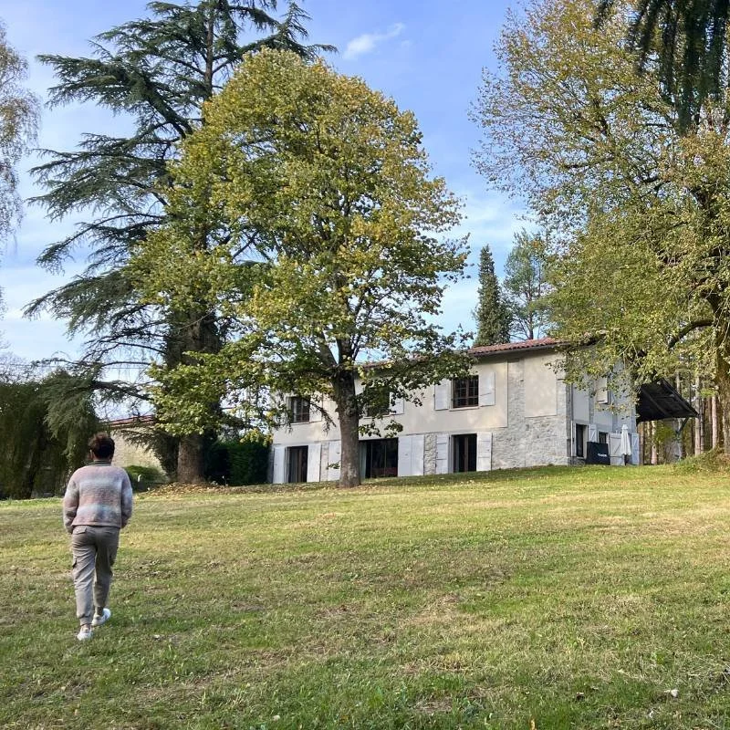 Woman walking on grass up hill to house.