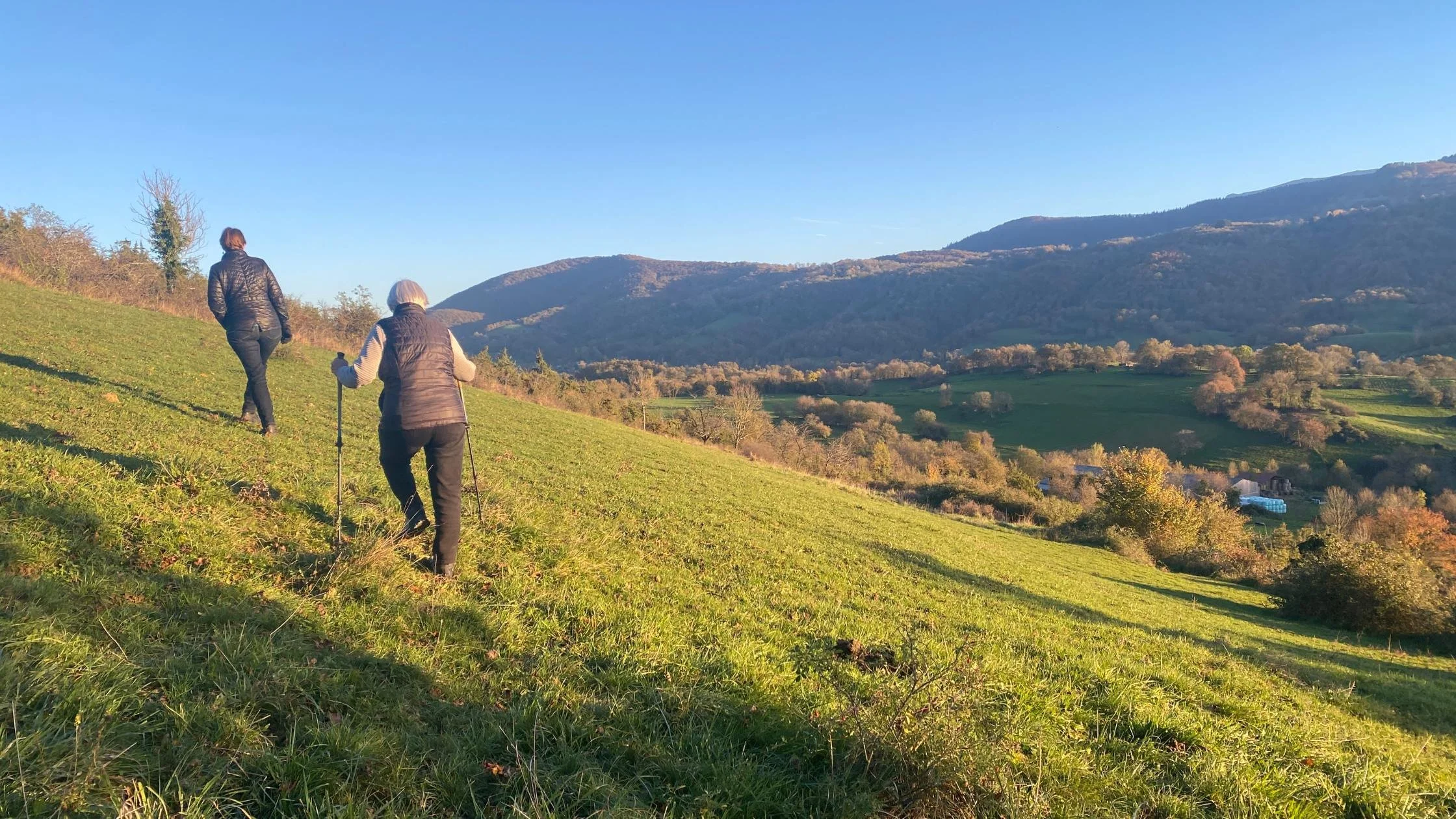 two women hiking up the side of a green hill during an Athara adventure trip