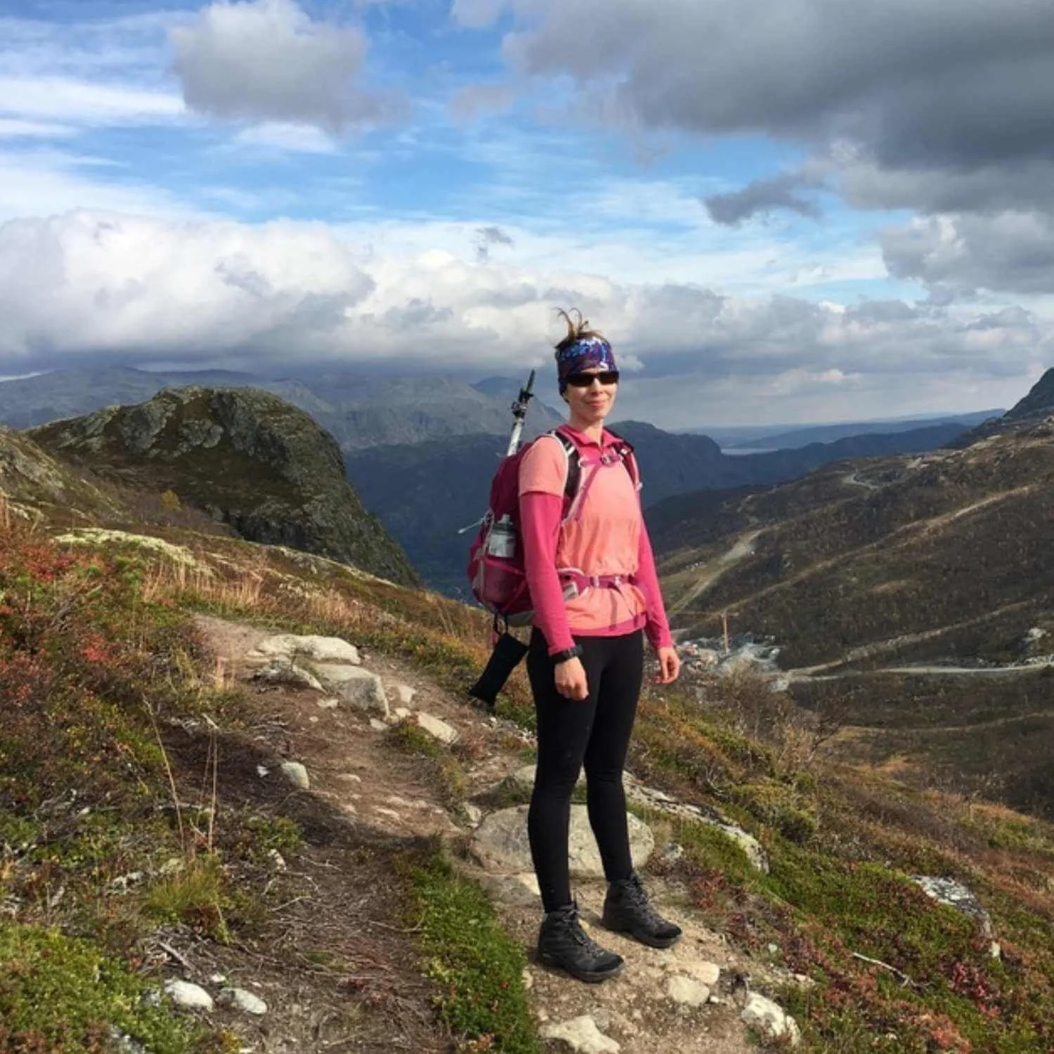 Seoka hiking on a mountain trail during an Athara women’s retreat in Europe, overlooking a wide valley and alpine landscape.