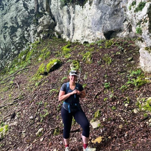 One female hiker smiling while standing at the base of a trail.