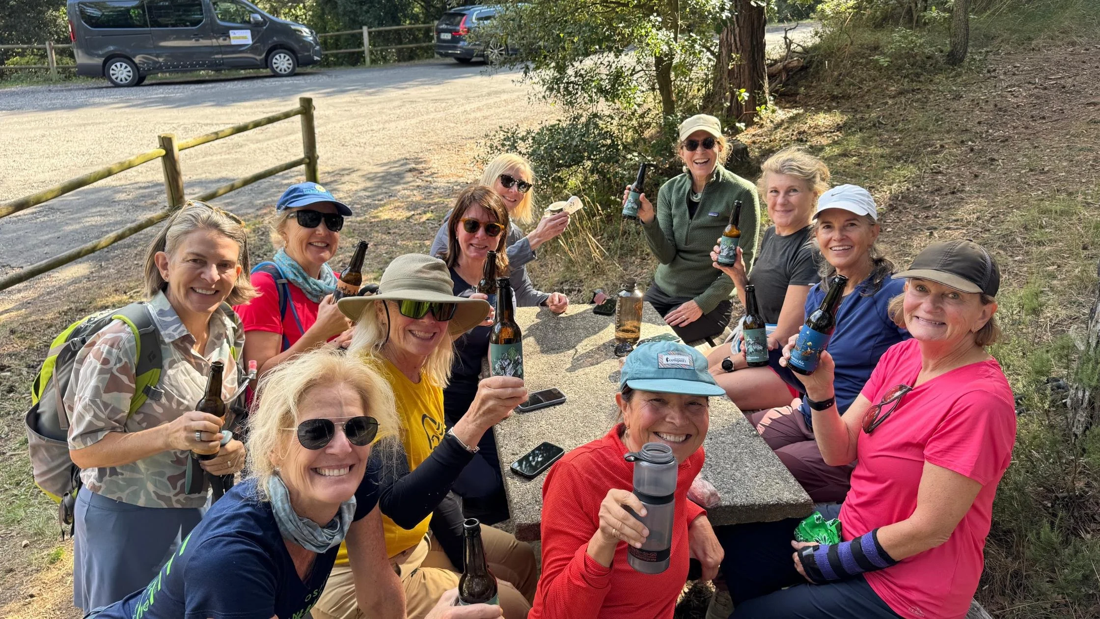 Smiling midlife women drinking beers after their hike.