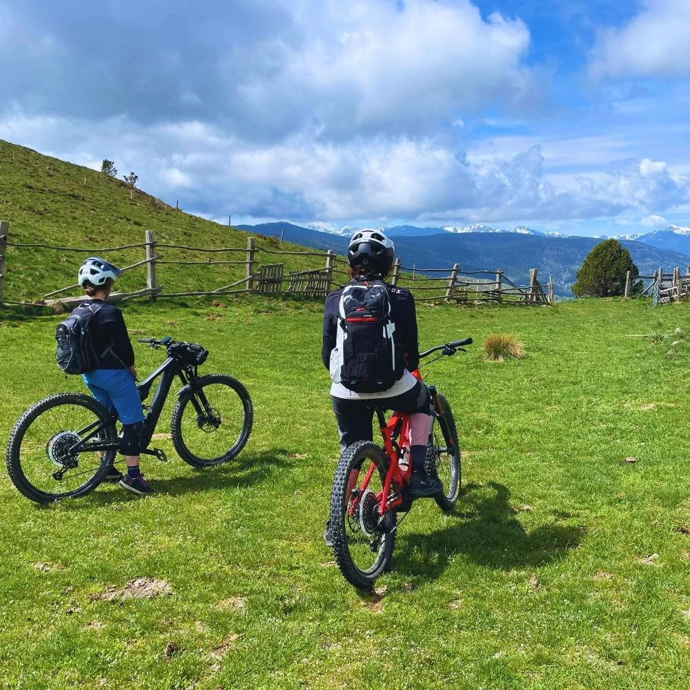 Two female mountain bikers looking ahead at the Pyrenees mountains.