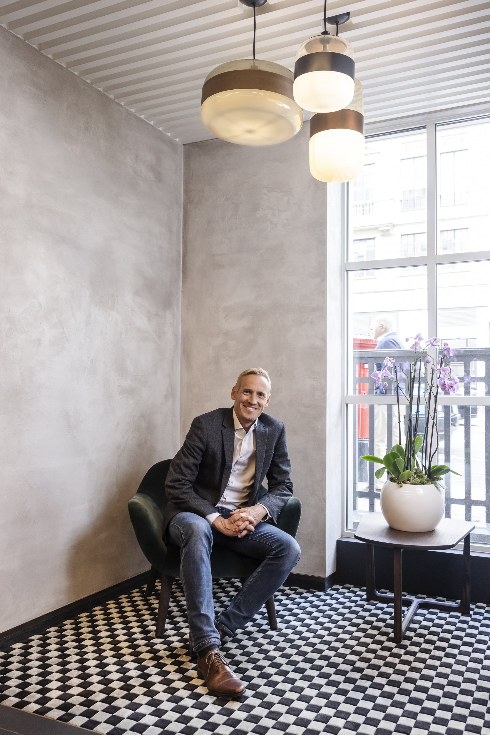 A corporate portrait of man sitting in chair in corner, corporate portrait