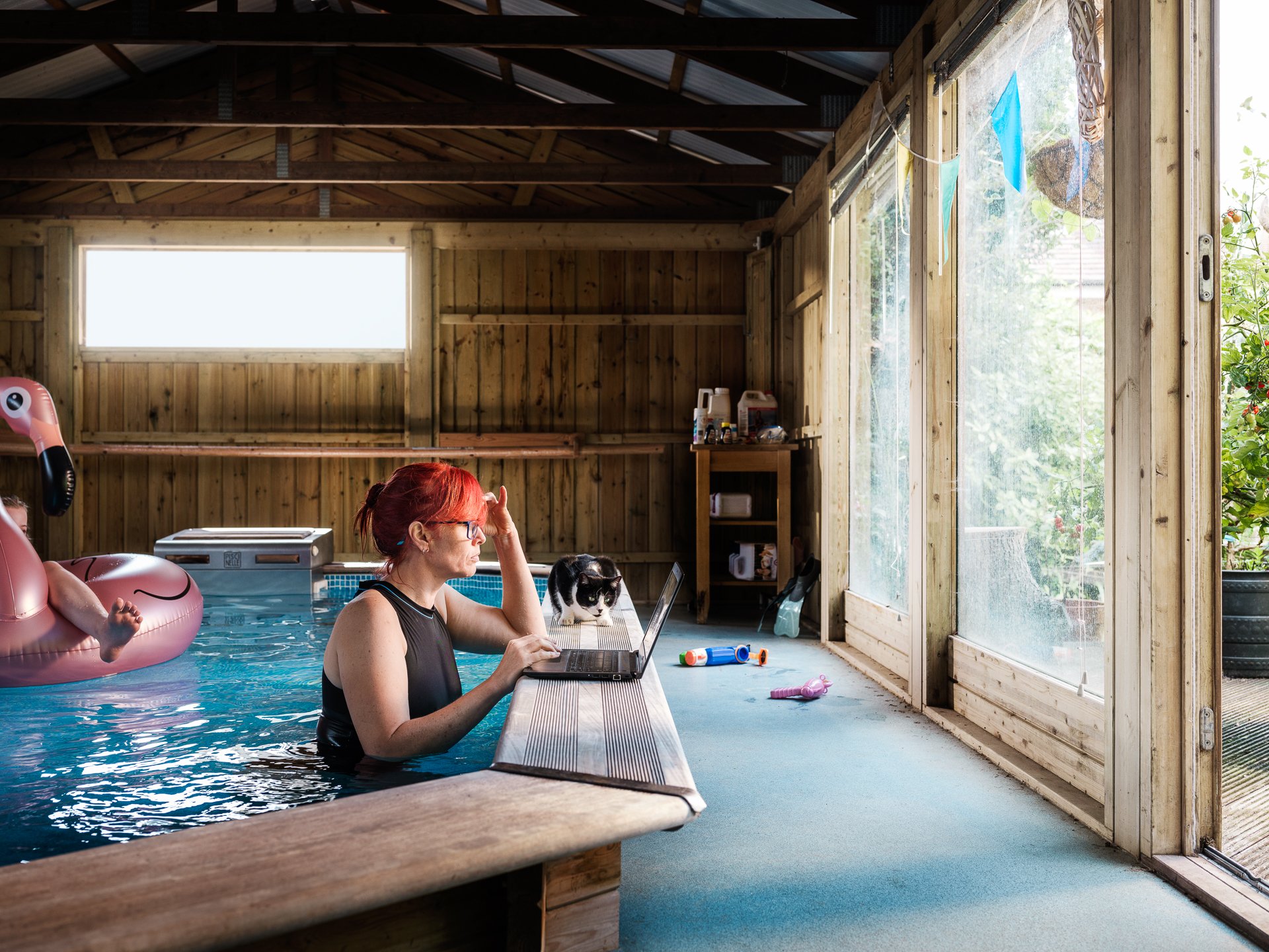 Lifestyle photo of lady using laptop from indoor pool