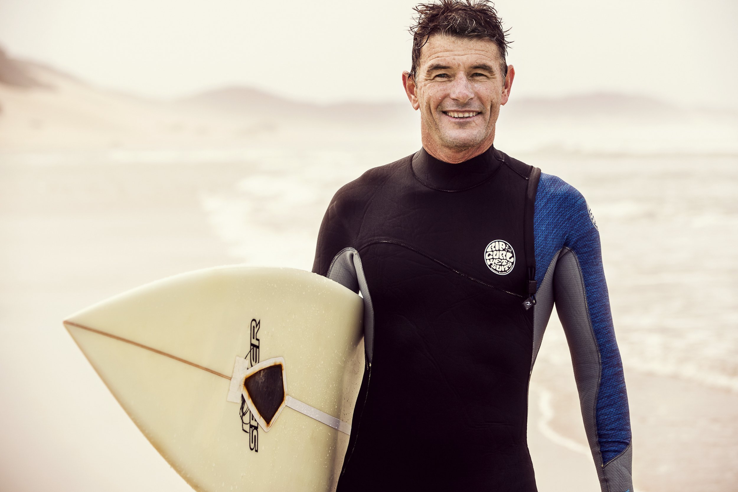Lifestyle portrait of middle-aged man with surf board