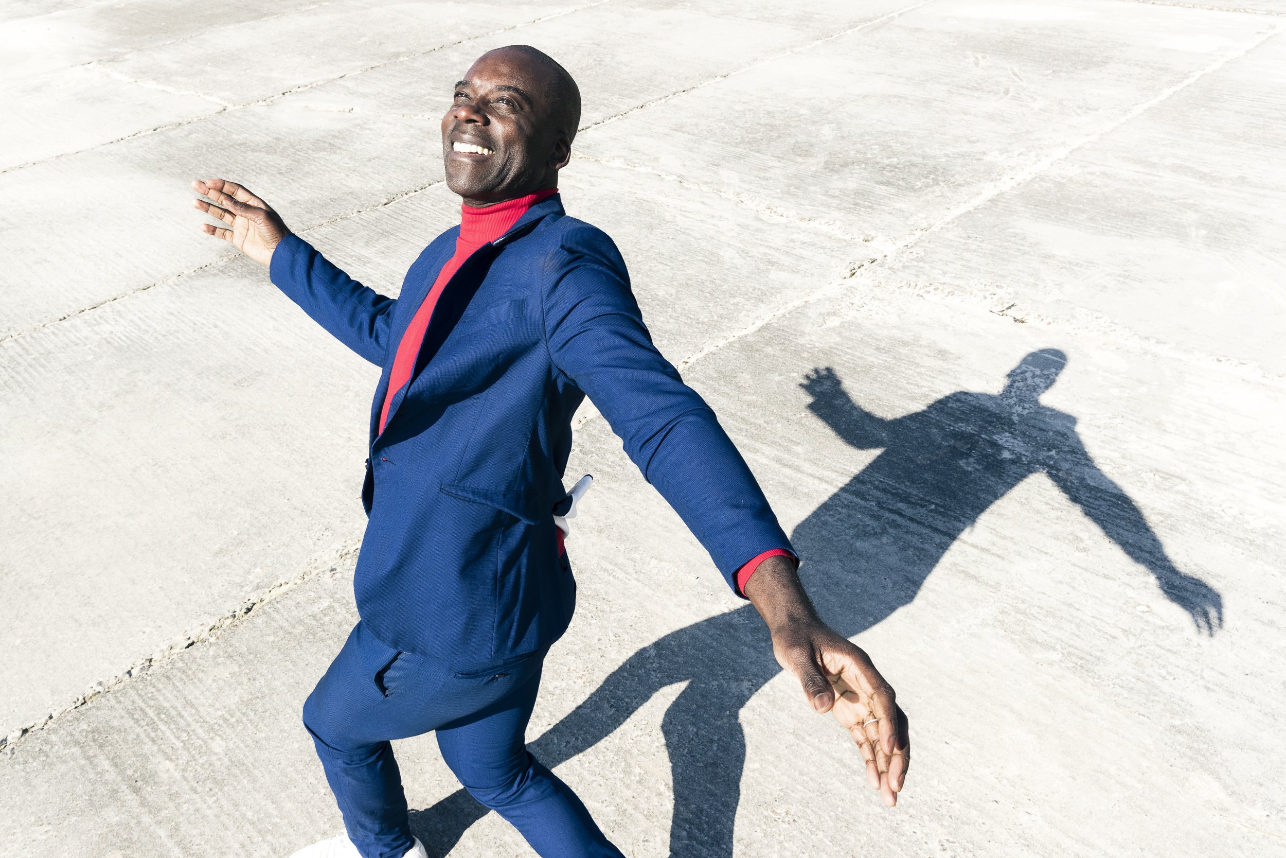 Lifestyle photo of man in suit dances on concrete