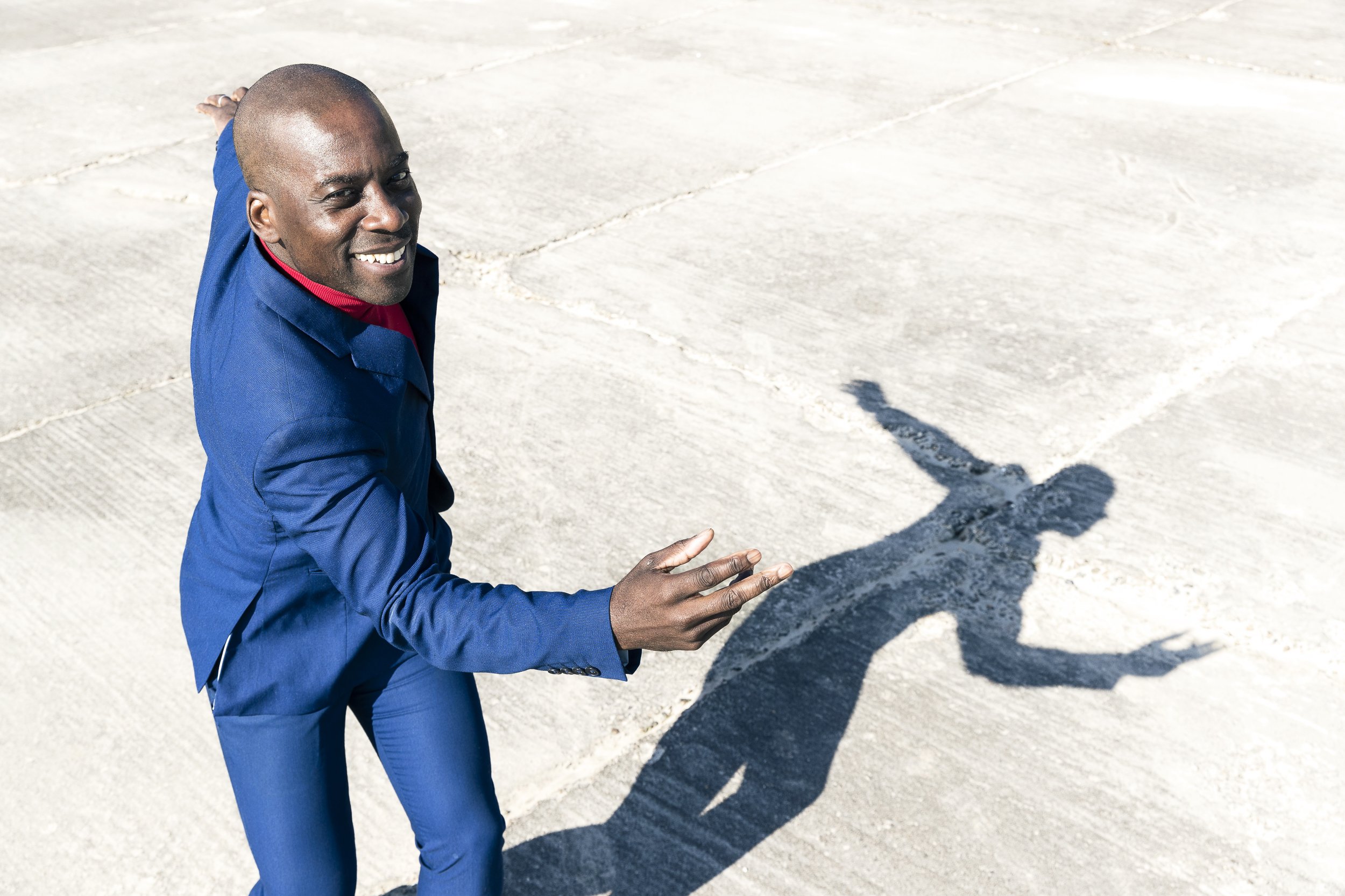 Lifestyle photo of man in suit dances on concrete