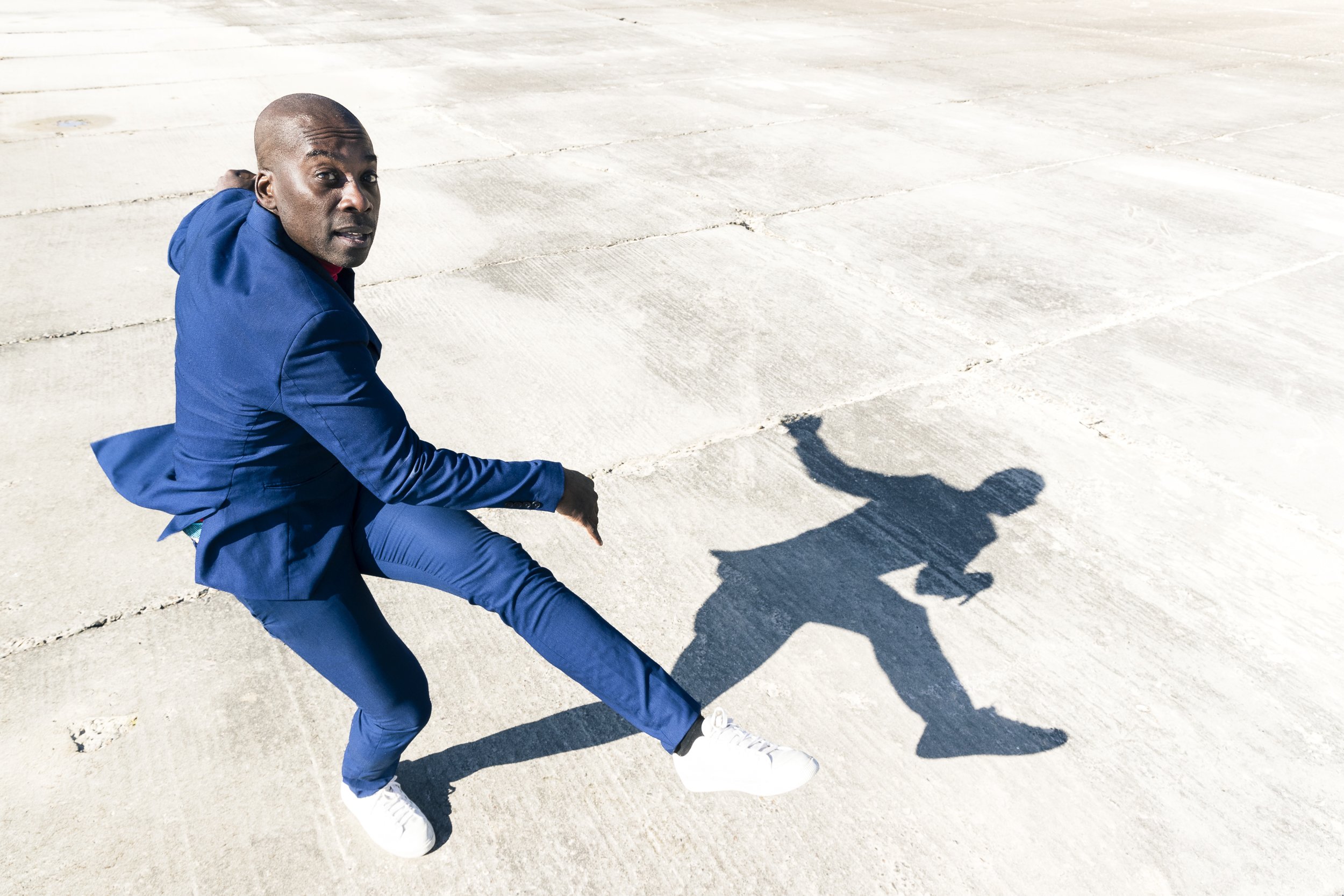 Lifestyle photo of man in suit dances on concrete 