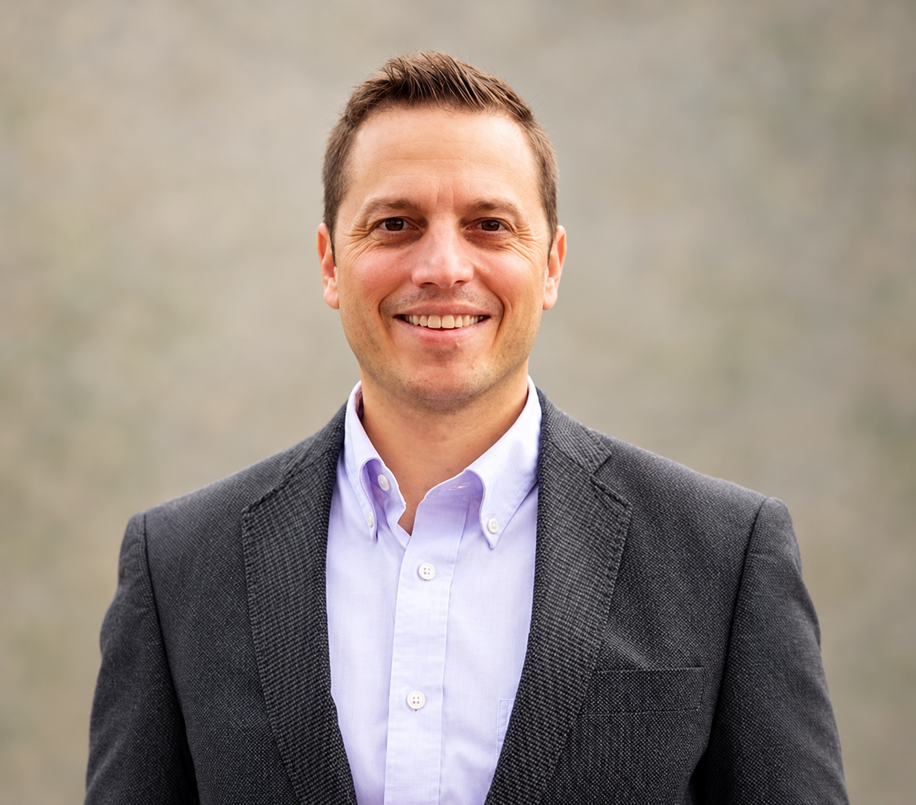 Christopher Harris, PhD, LPC, smiling in a dark blazer against a soft neutral background.