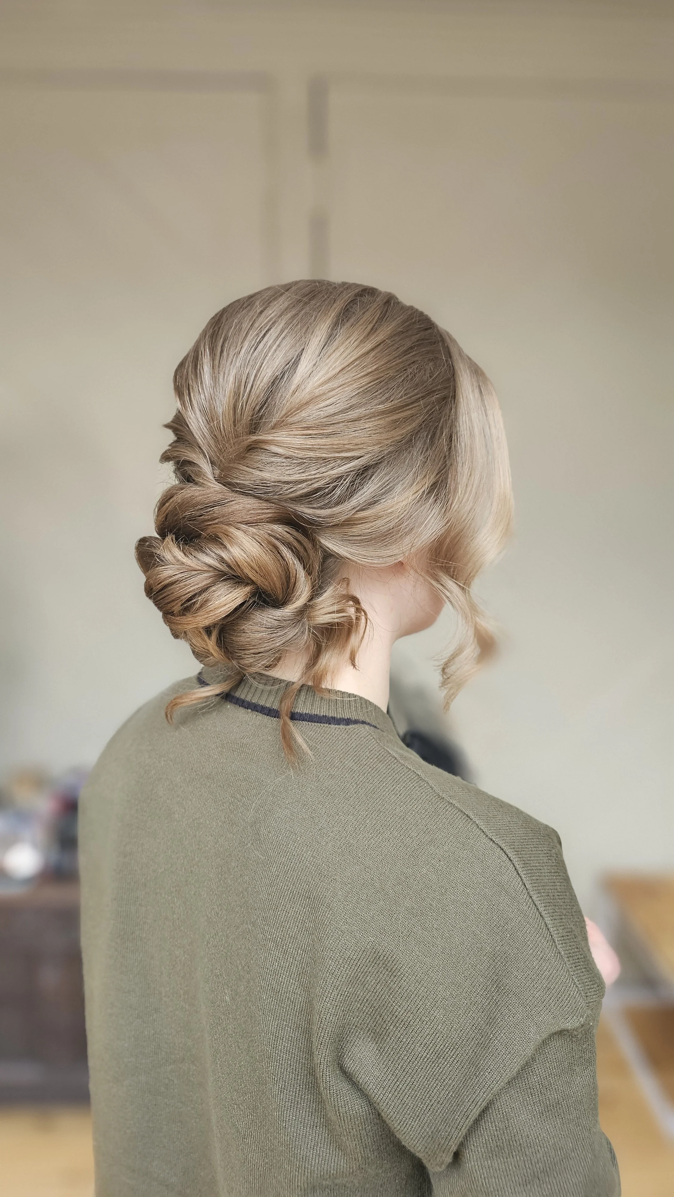Back of a woman with her hair styled in an elegant twisted updo, wearing a green top.