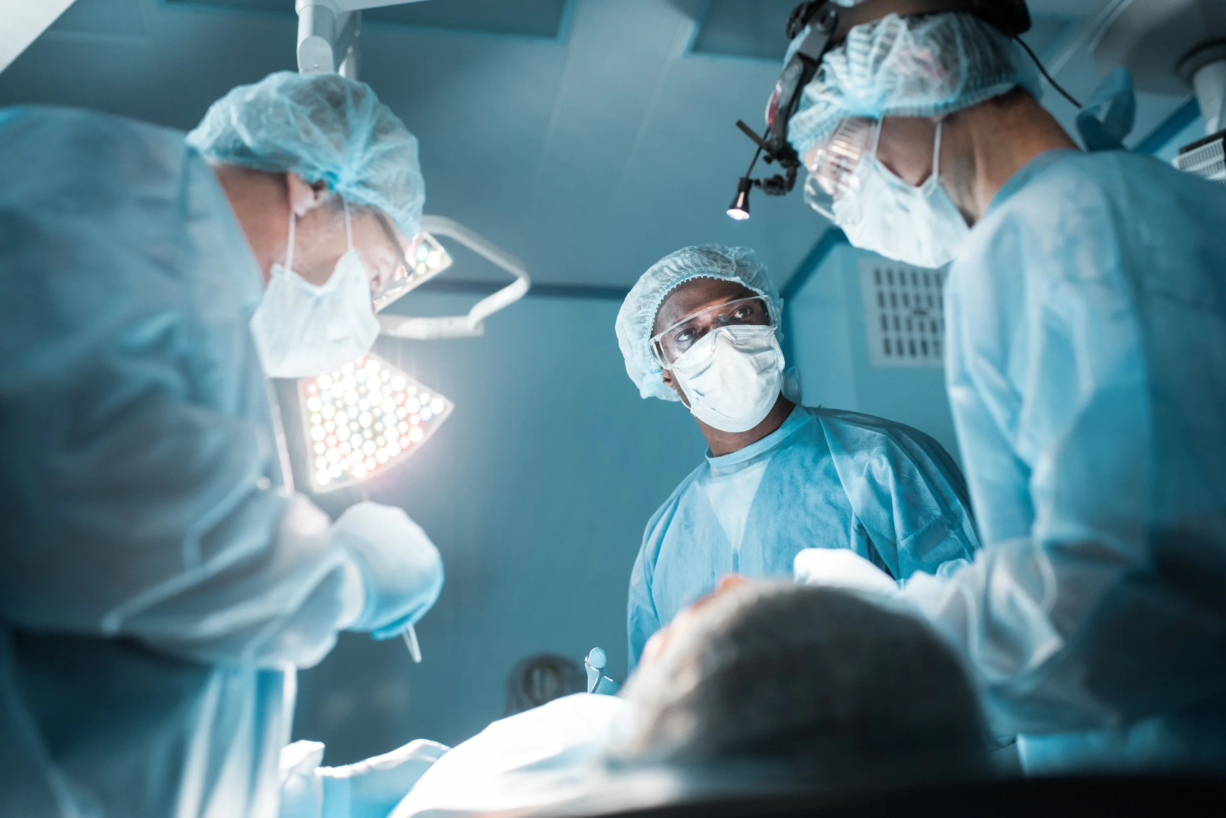 Surgeons performing an operation in an operating room with bright surgical lights.