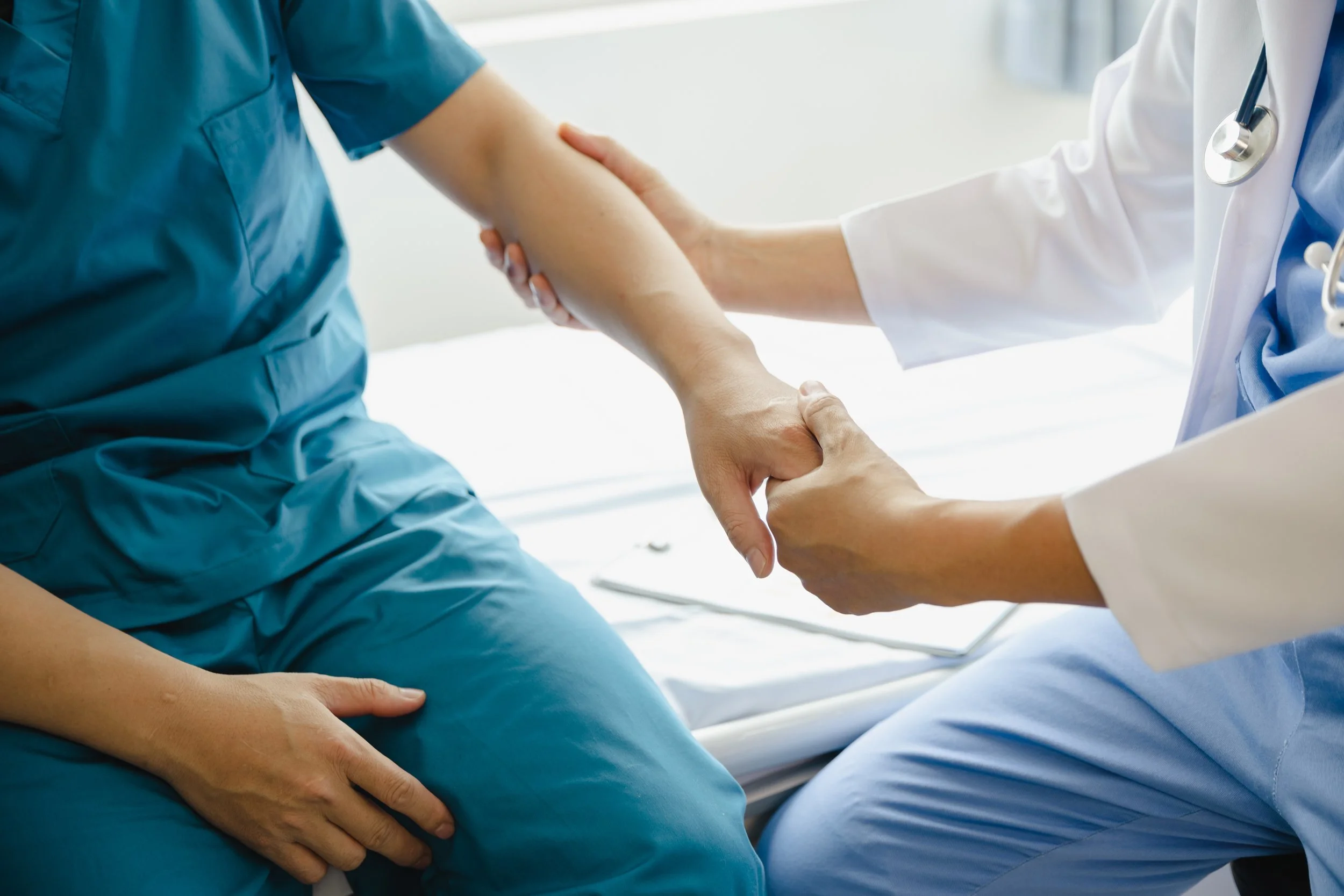 Doctor holding a patient's arm for examination in a medical setting.