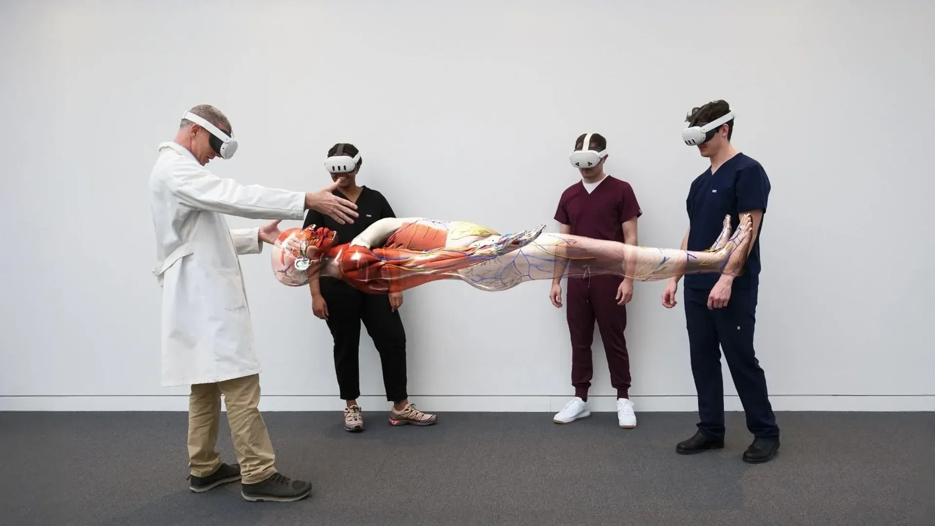 Medical professionals wearing XR headsets demonstrate a virtual human body lying on a table, with a doctor pointing towards it and three others observing.