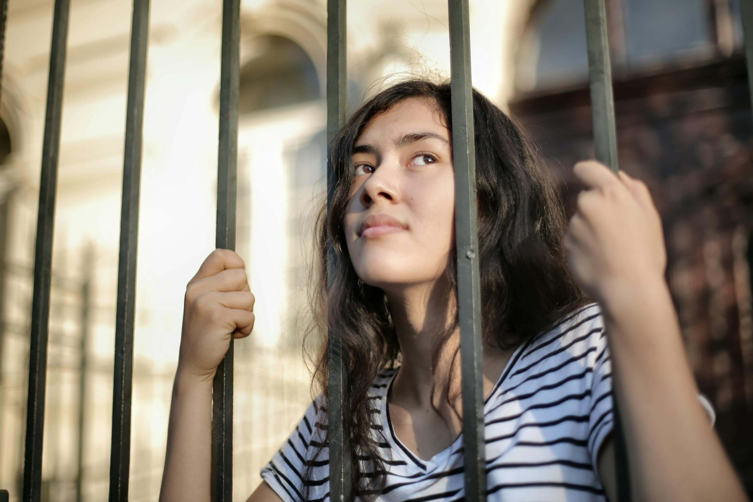 A young woman grips metal bars and gazes upward with a longing, reflective expression. Is your teen feeling trapped, stuck, or unable to move forward? A teen therapist in San Ramon, CA, can provide the support needed to break free.