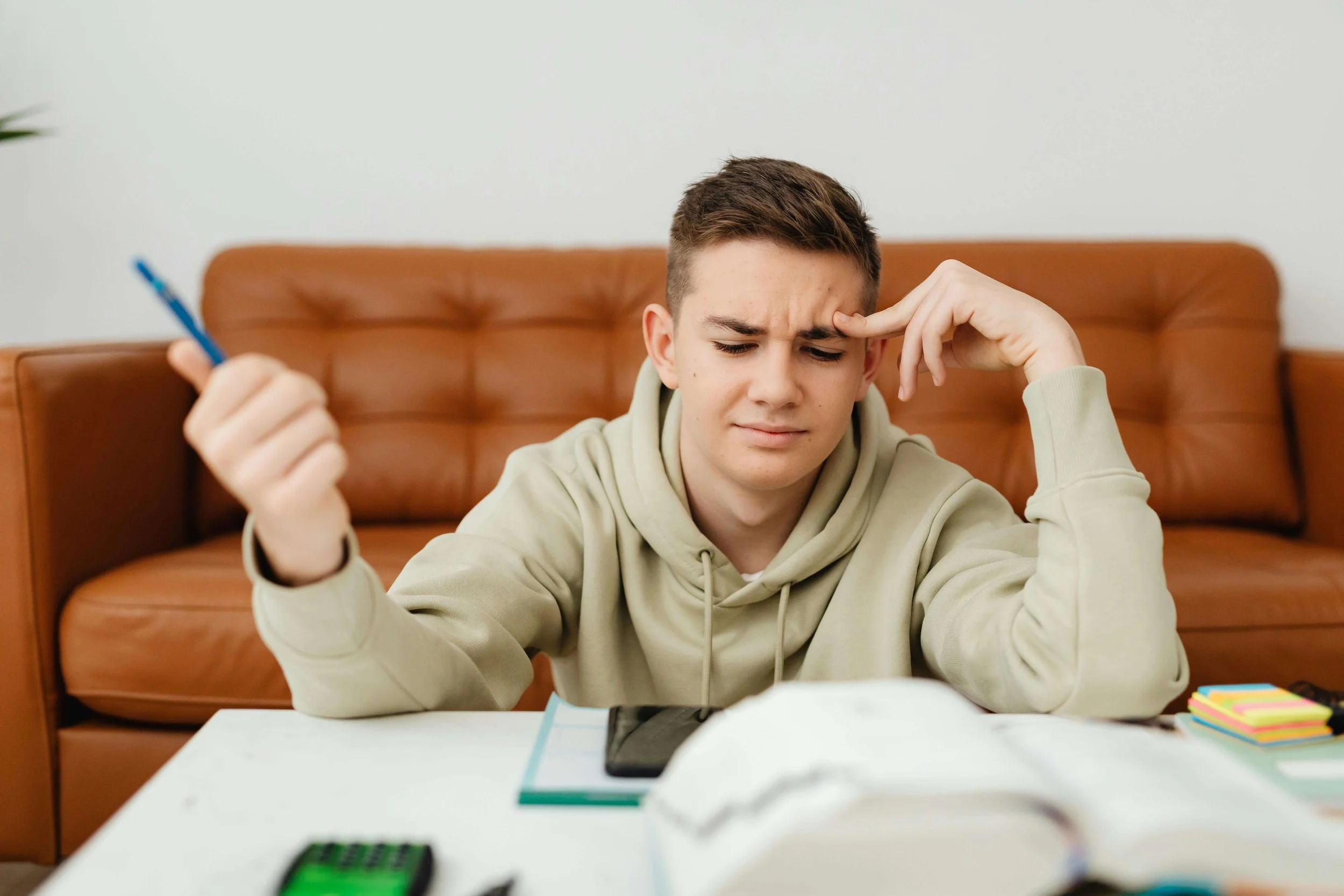 A male teen looking overwhelmed while doing homework. Is your teen a perfectionist? Meet with a teen therapist in San Ramon, CA, to explore causes, effects, and solutions for perfectionism in teens.