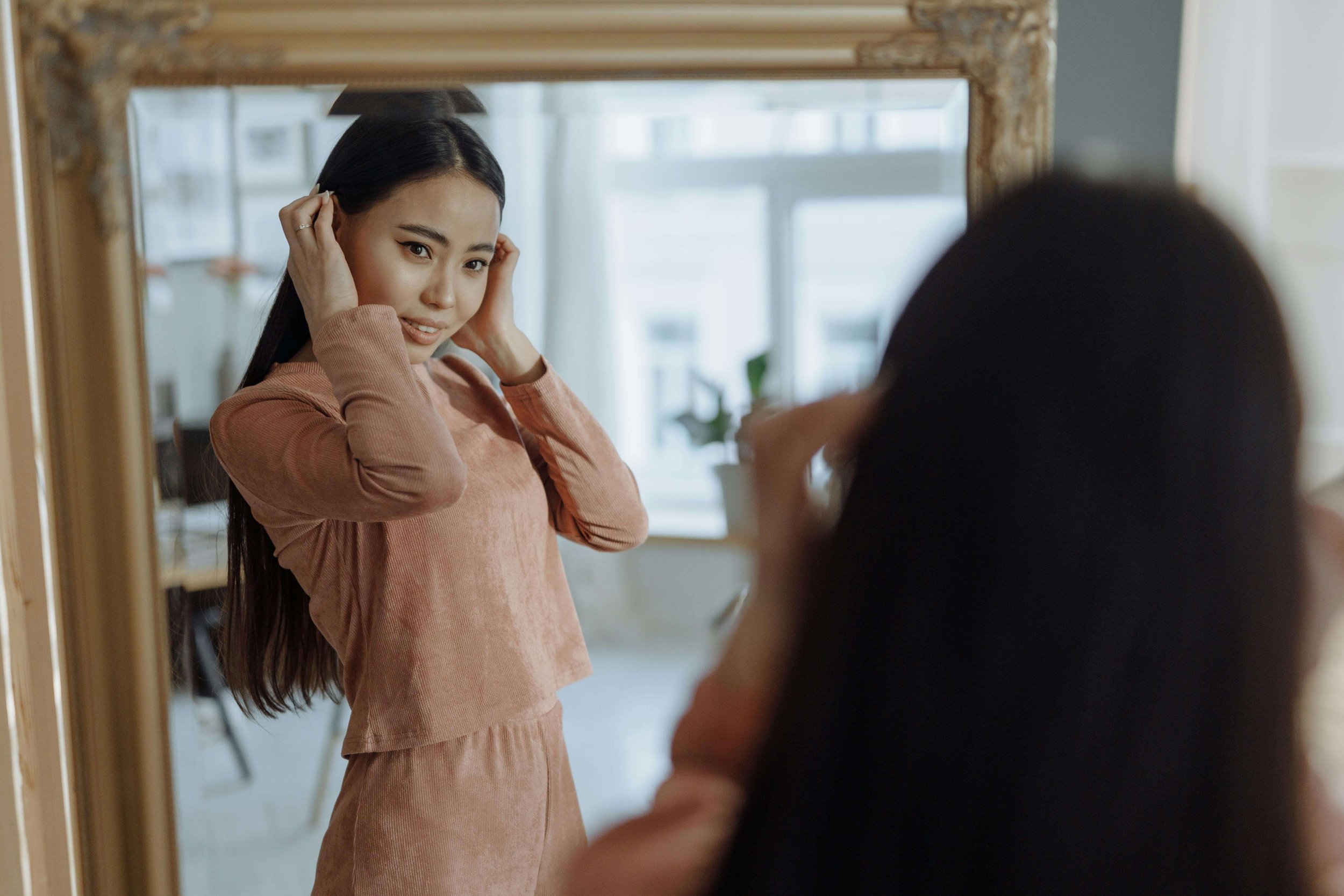 A young woman adjusts her hair in a mirror. How does perfectionism distort the way teens see themselves when they look in the mirror? A teen therapist in San Ramon, CA can help your teen build real, lasting self-esteem.
