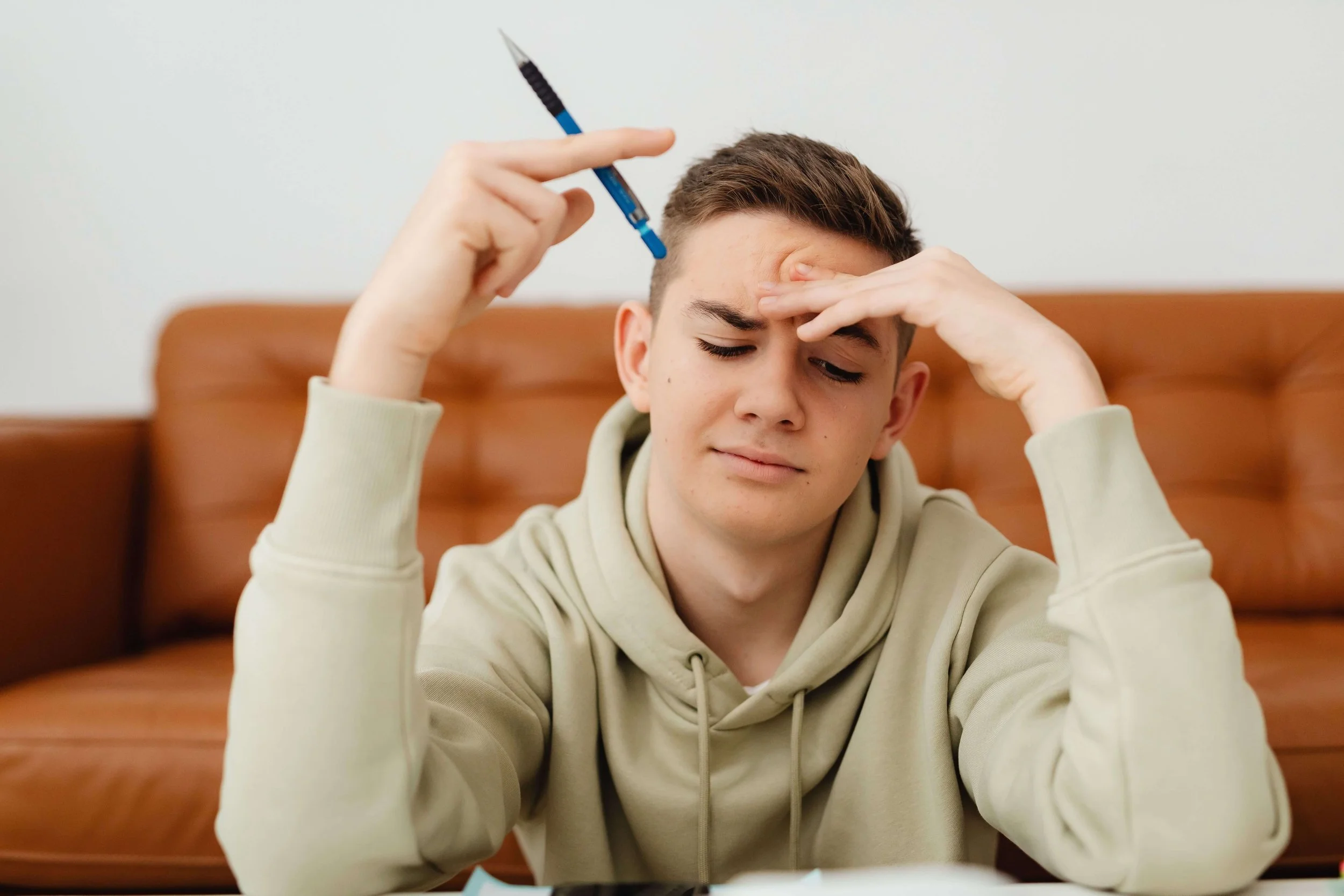 A teenage boy looking down with an overwhelmed expression on his face.
