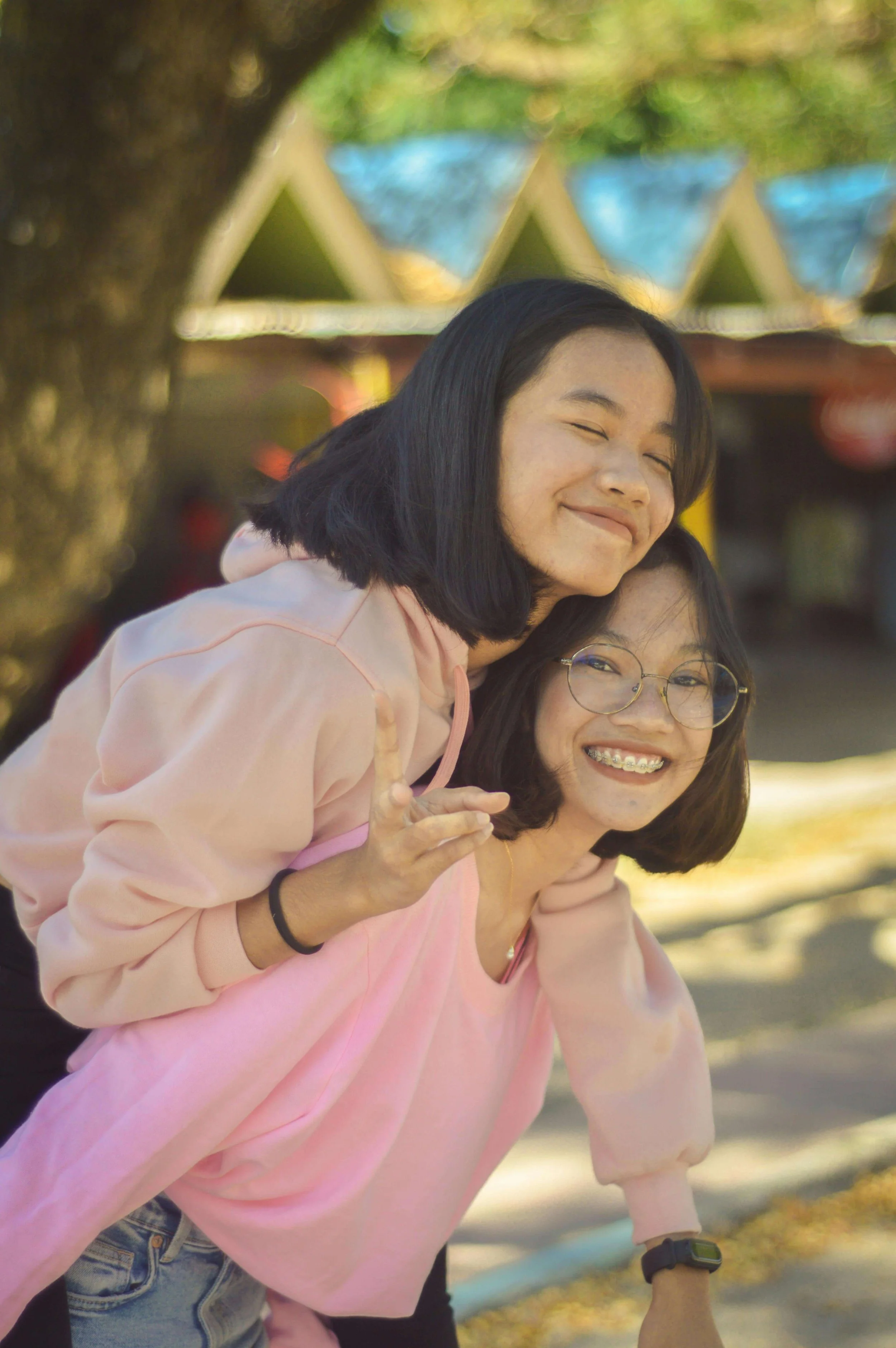Two teenage girls laughing and hugging outdoors, enjoying a carefree moment together. Can positive friendships help reduce teen anger before it escalates? Learn more with a teen therapist in San Ramon, CA.