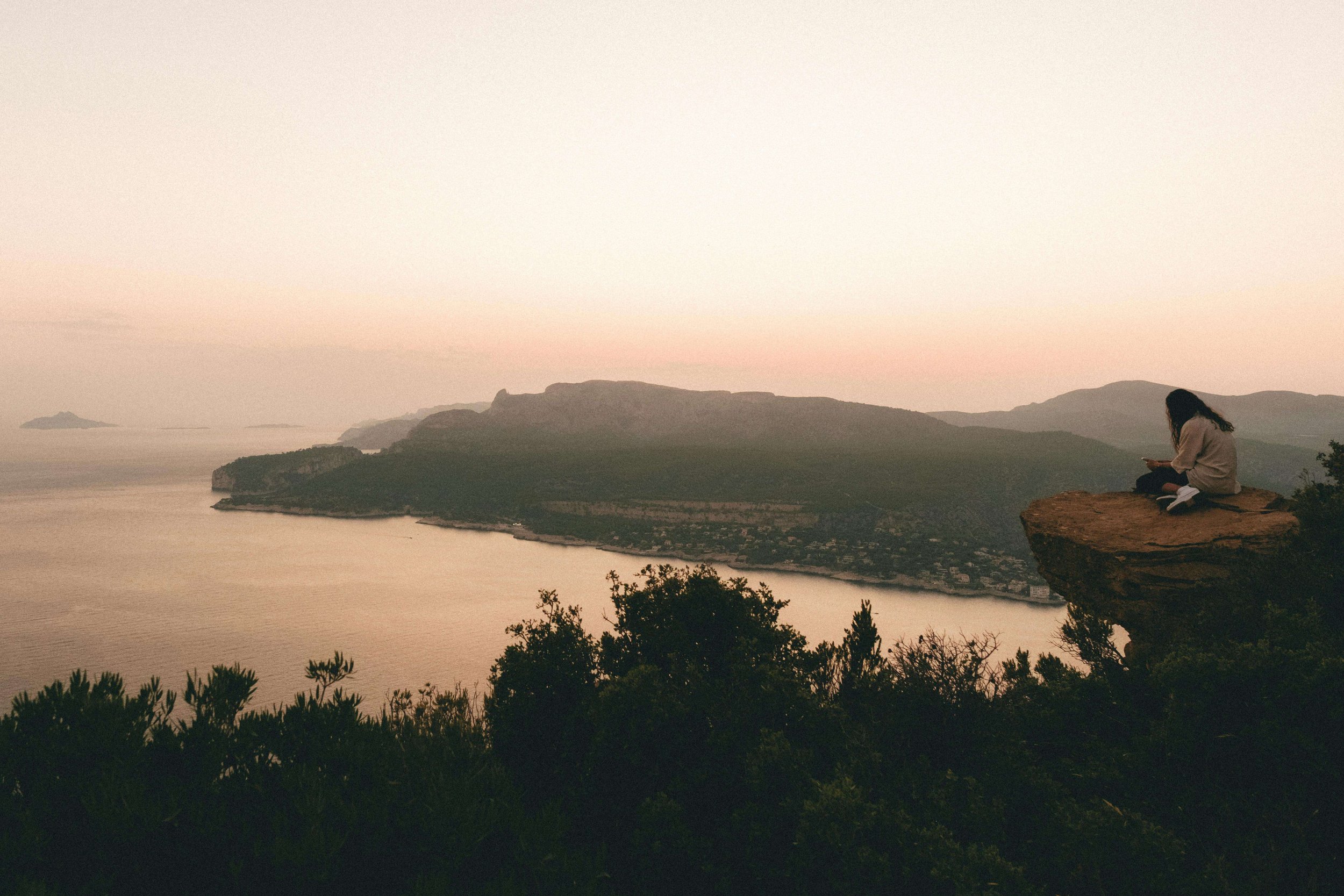 A young woman sits alone on the edge of a dramatic cliff. Is your teen acting in ways that affect the whole family? An Asian teen therapist in San Ramon, CA, can help you understand what's driving the behavior and how to reconnect with them.