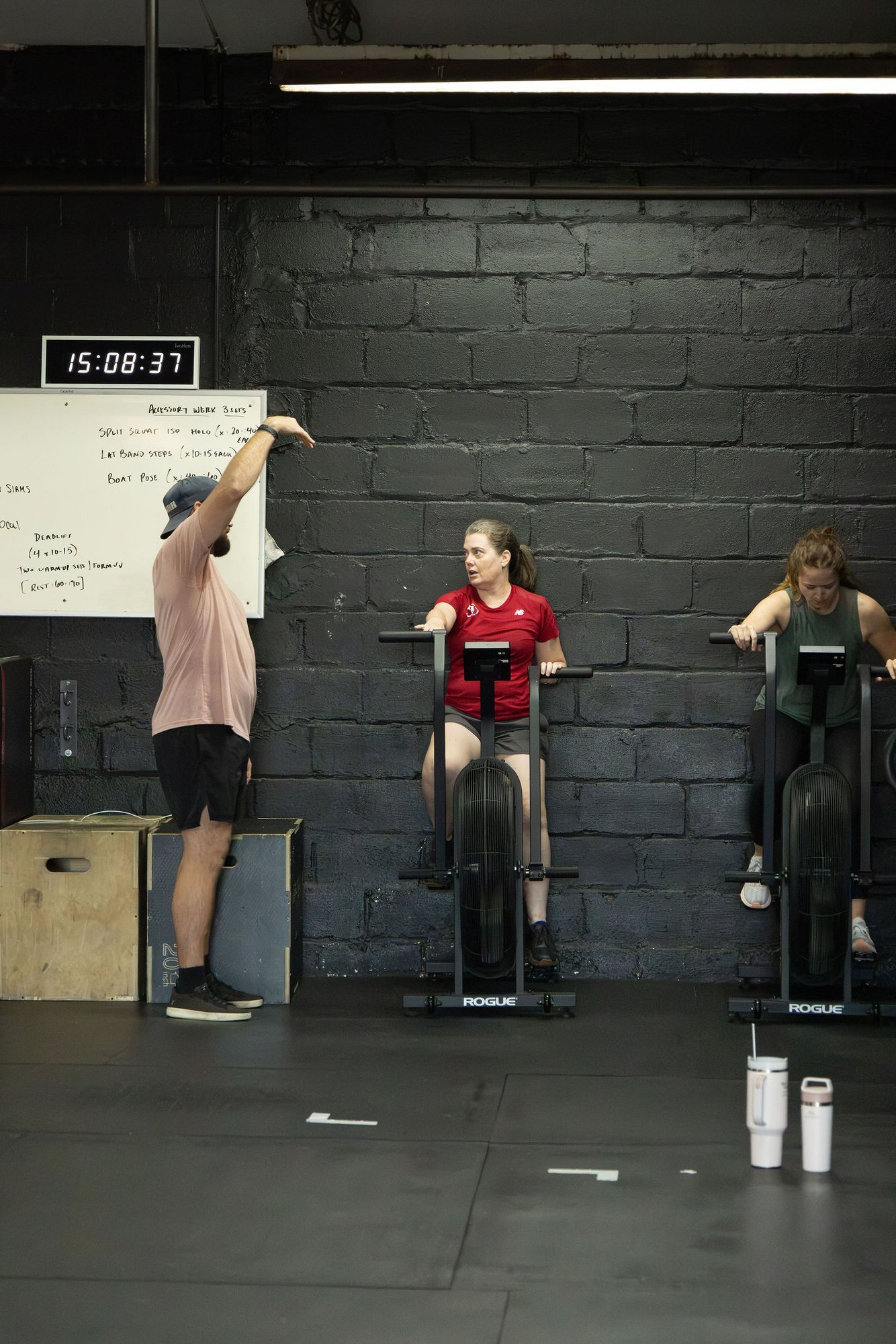Coach leading two members on air bikes during a small group class at Char Fitness Club in Montclair, NJ