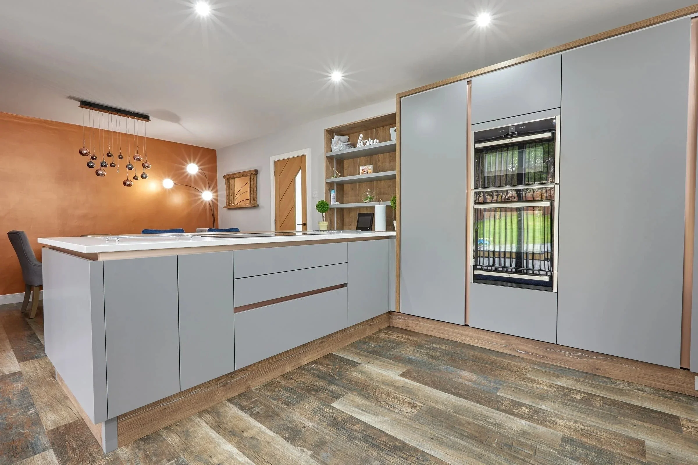 Contemporary grey handleless kitchen with wood accents and island installation by Fineline Interiors Warrington