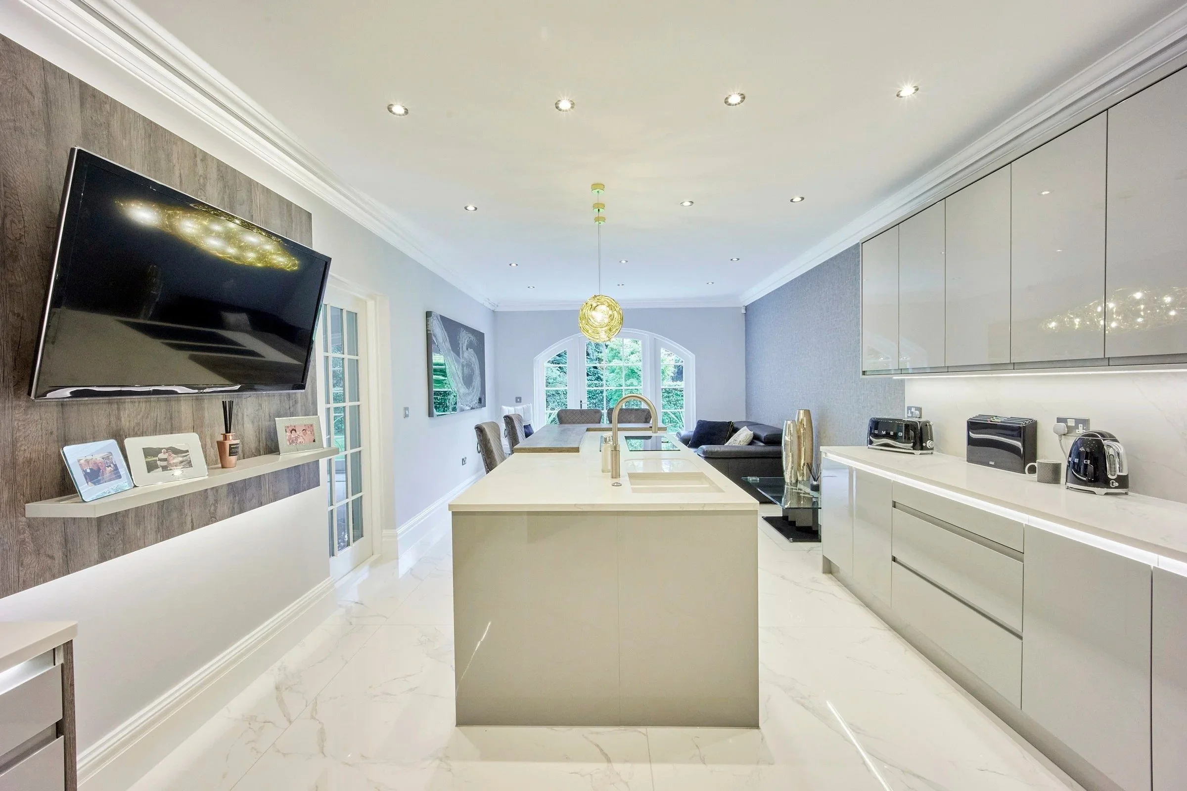Modern open-plan kitchen with sleek island and gloss cabinetry designed by Fineline Interiors Warrington