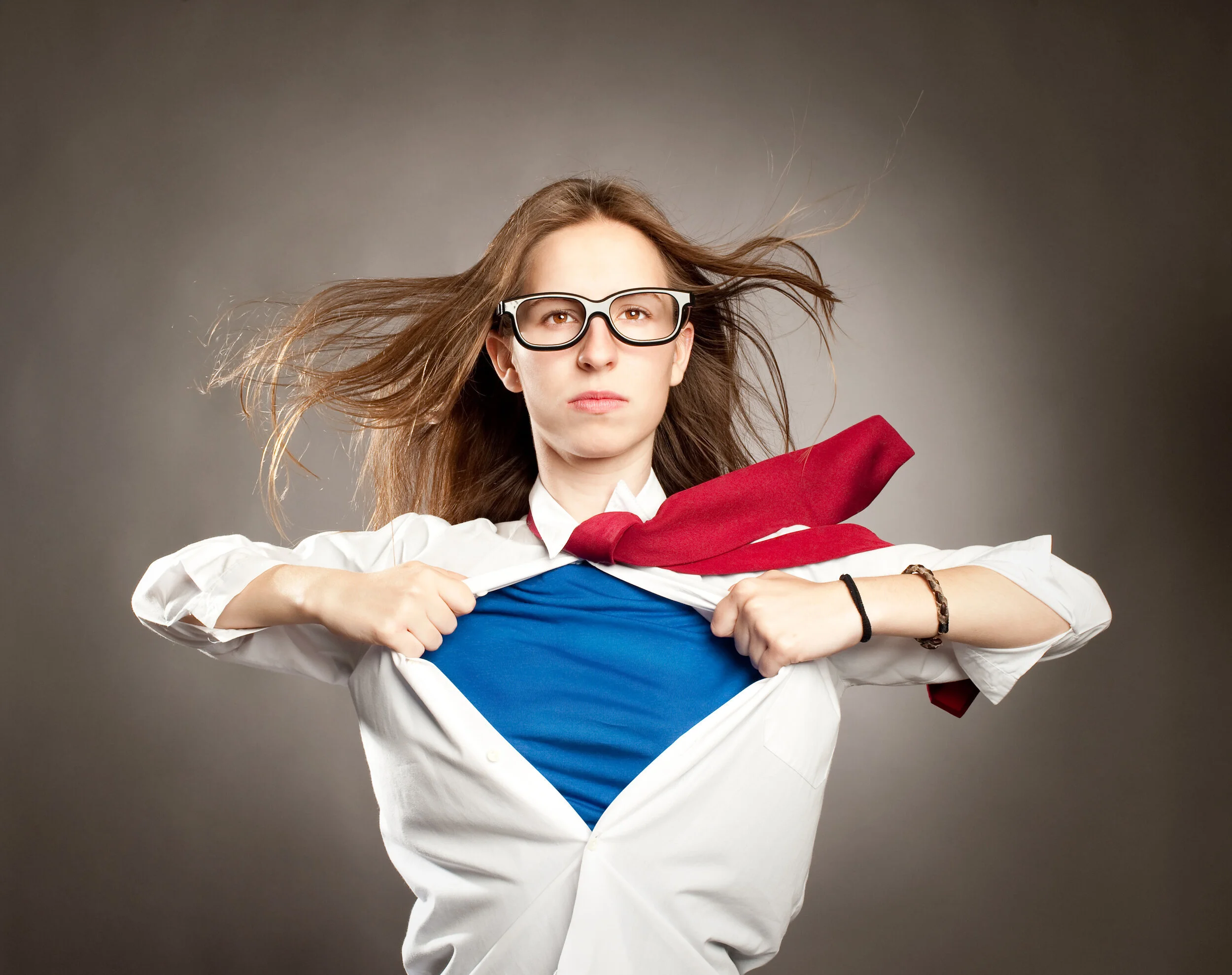 A woman accesses a strong power pose looking like Superman