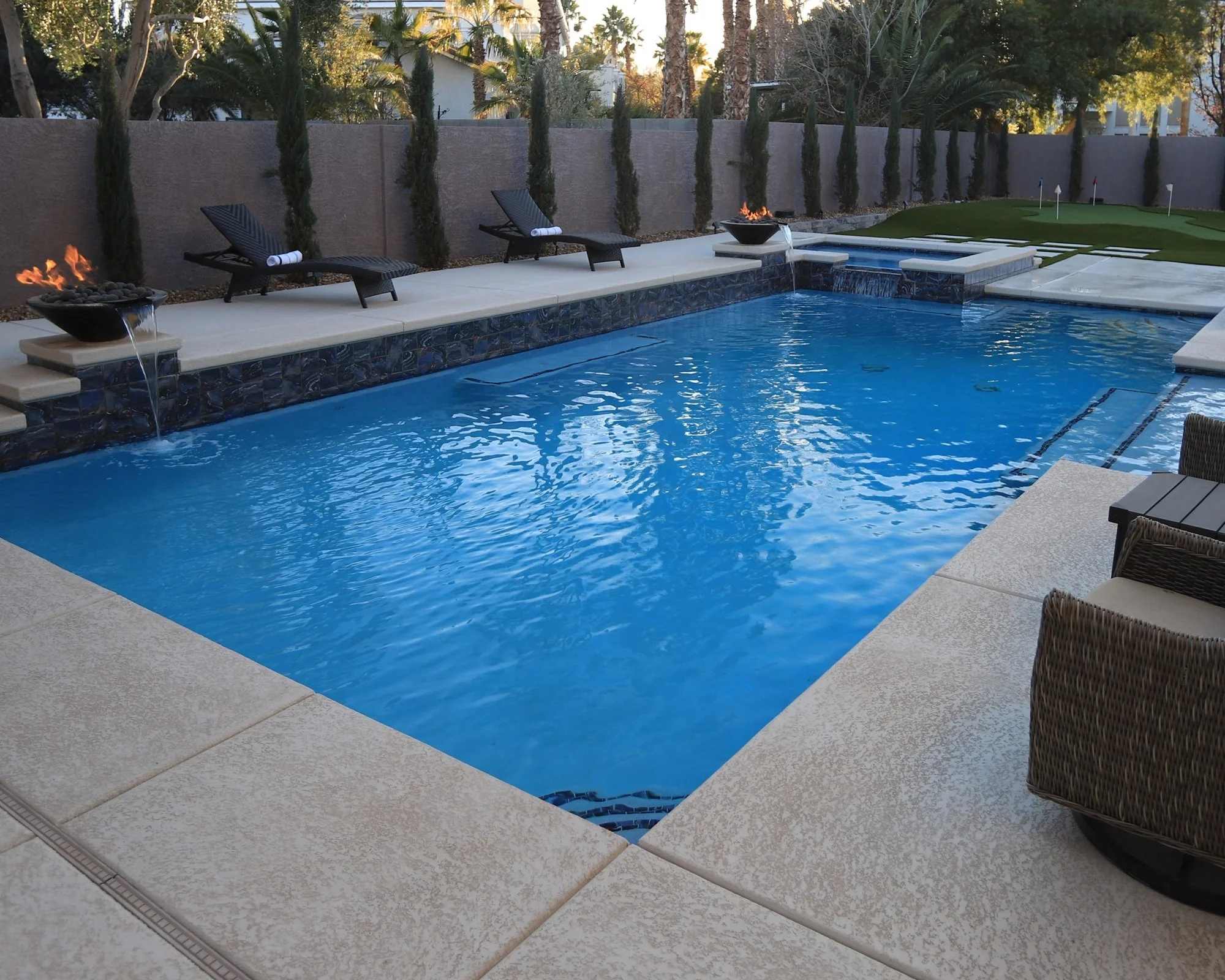 A remodeled backyard swimming pool with with LED lights, fire elements, new interior finish and tile.