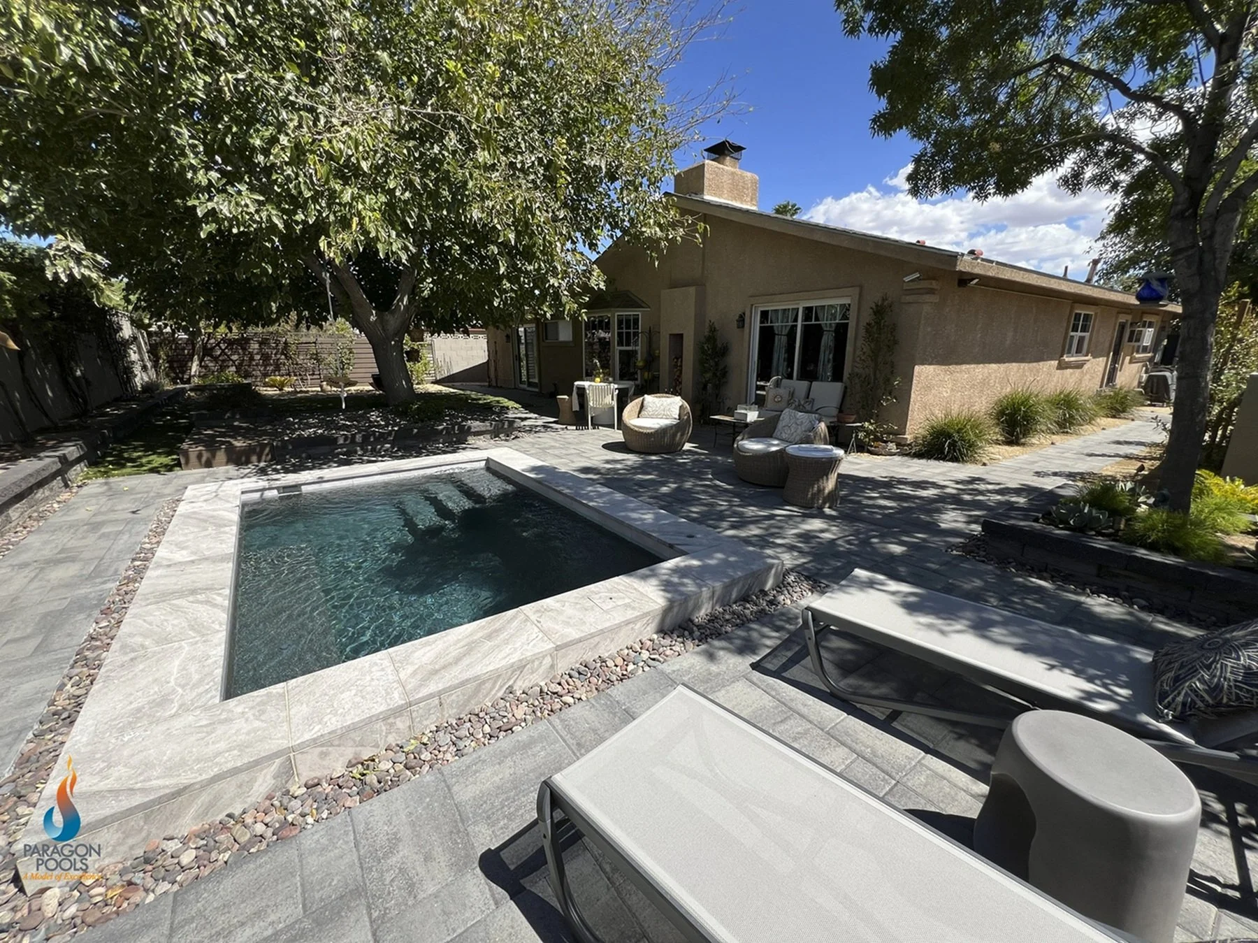 Residential backyard with a small custom spool- combination spa and pool, outdoor furniture, trees.