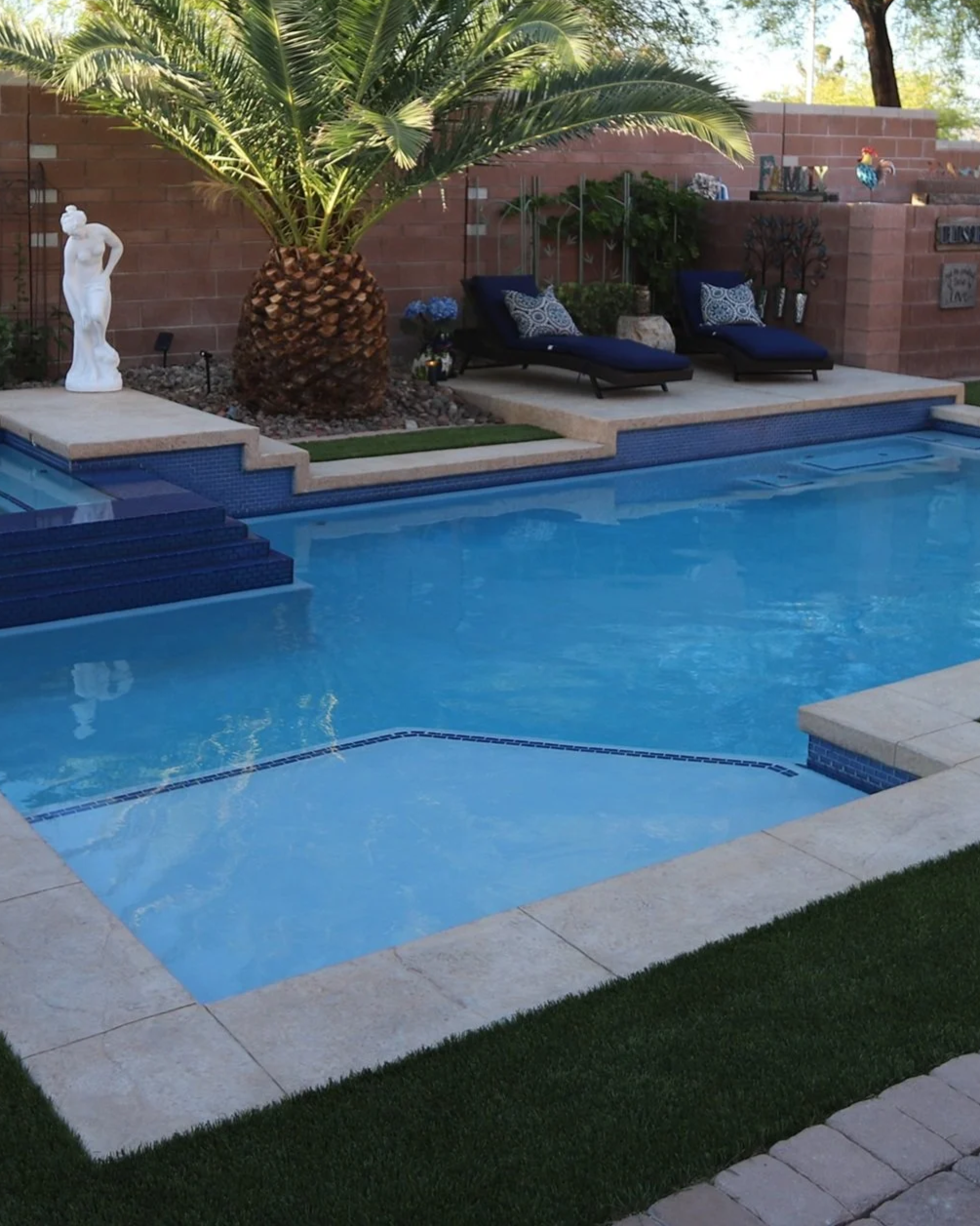 A custom backyard swimming pool with new interior finish, new LED lights, and new blue tile.