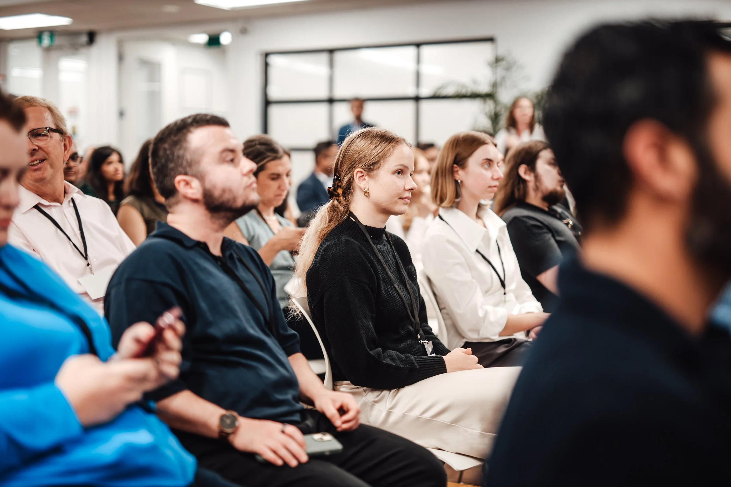 Audience members attending a conference or seminar, seated and listening attentively.