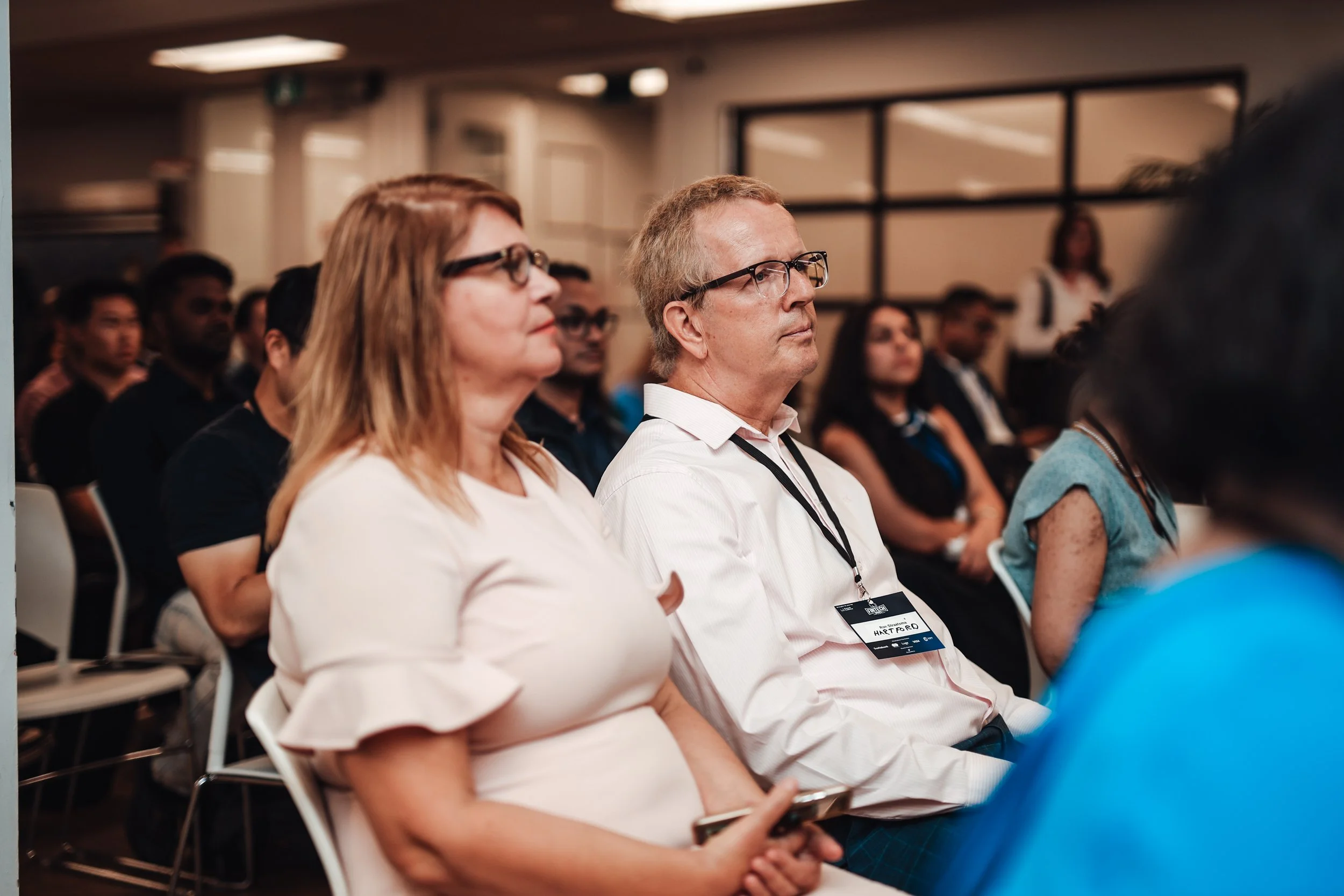 Attendees sitting in a conference room, listening to a presentation.