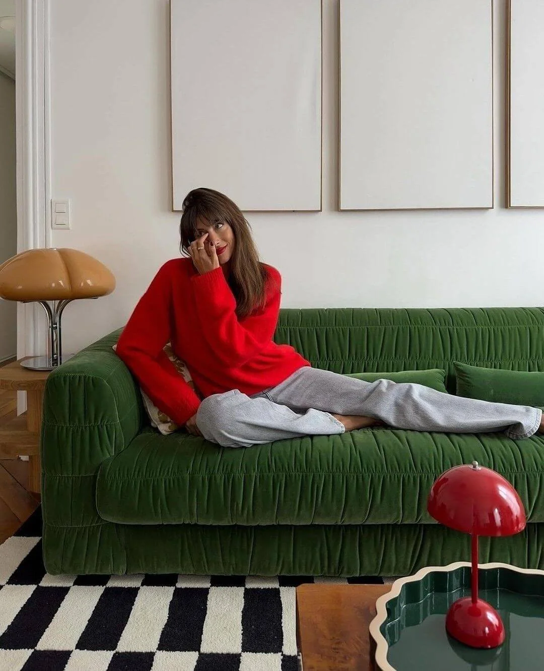 Woman in a red sweater relaxing on a green velvet sofa in a stylish living room representative of a person in therapy for complex trauma