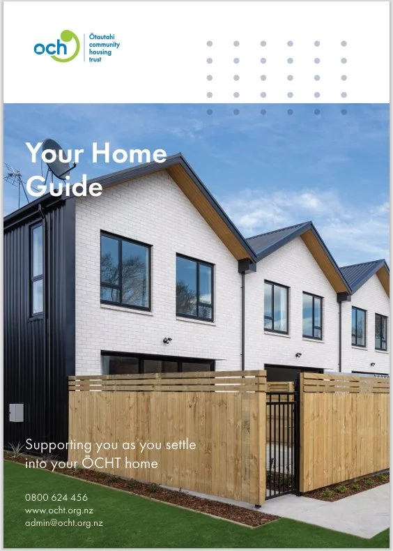 Front view of a modern residential building with white brick walls and black window frames, enclosed by a wooden fence, under a partly cloudy sky, for OCHT community housing trust.