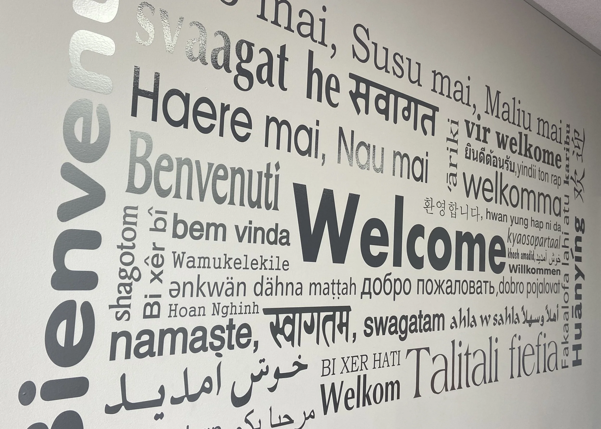Wall display with 'Welcome' written in multiple languages including English, Hindi, Thai, Arabic, Japanese, Korean, Russian, and others.