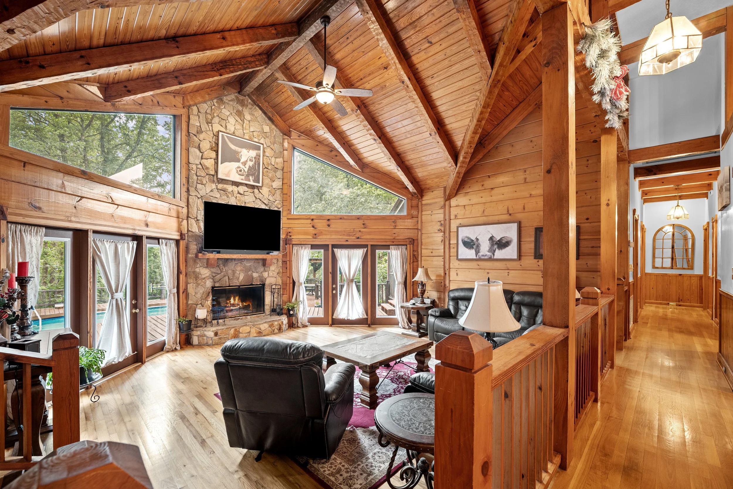 Rustic living room with vaulted wood ceilings, a stone fireplace, and an adjoining foyer.