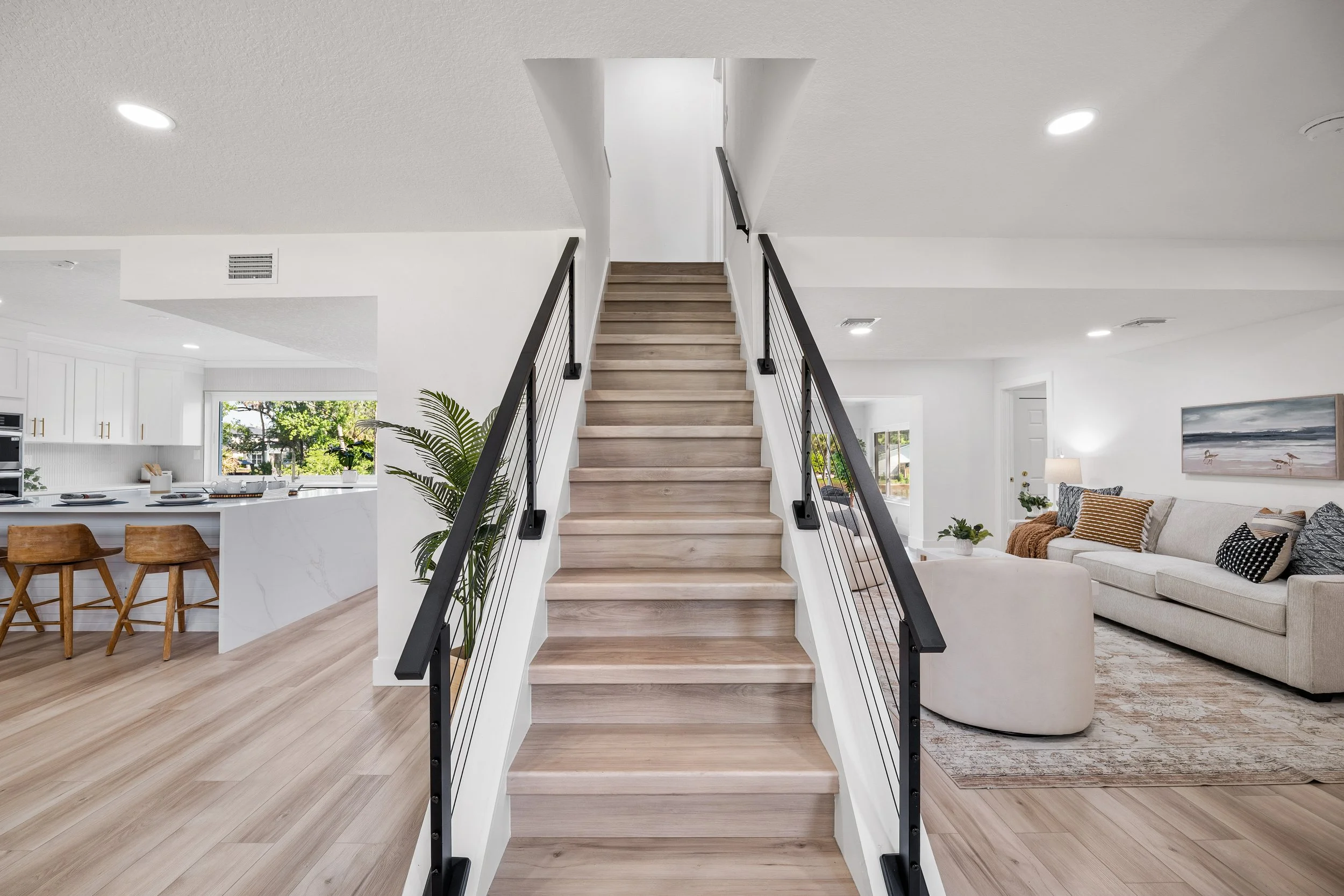 Modern staircase with white risers and wood treads opening onto a bright living area.