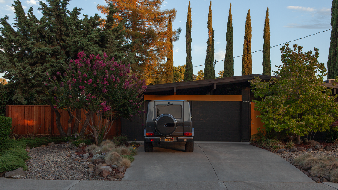 Restored midcentury Eichler at dusk with landscaped entry.