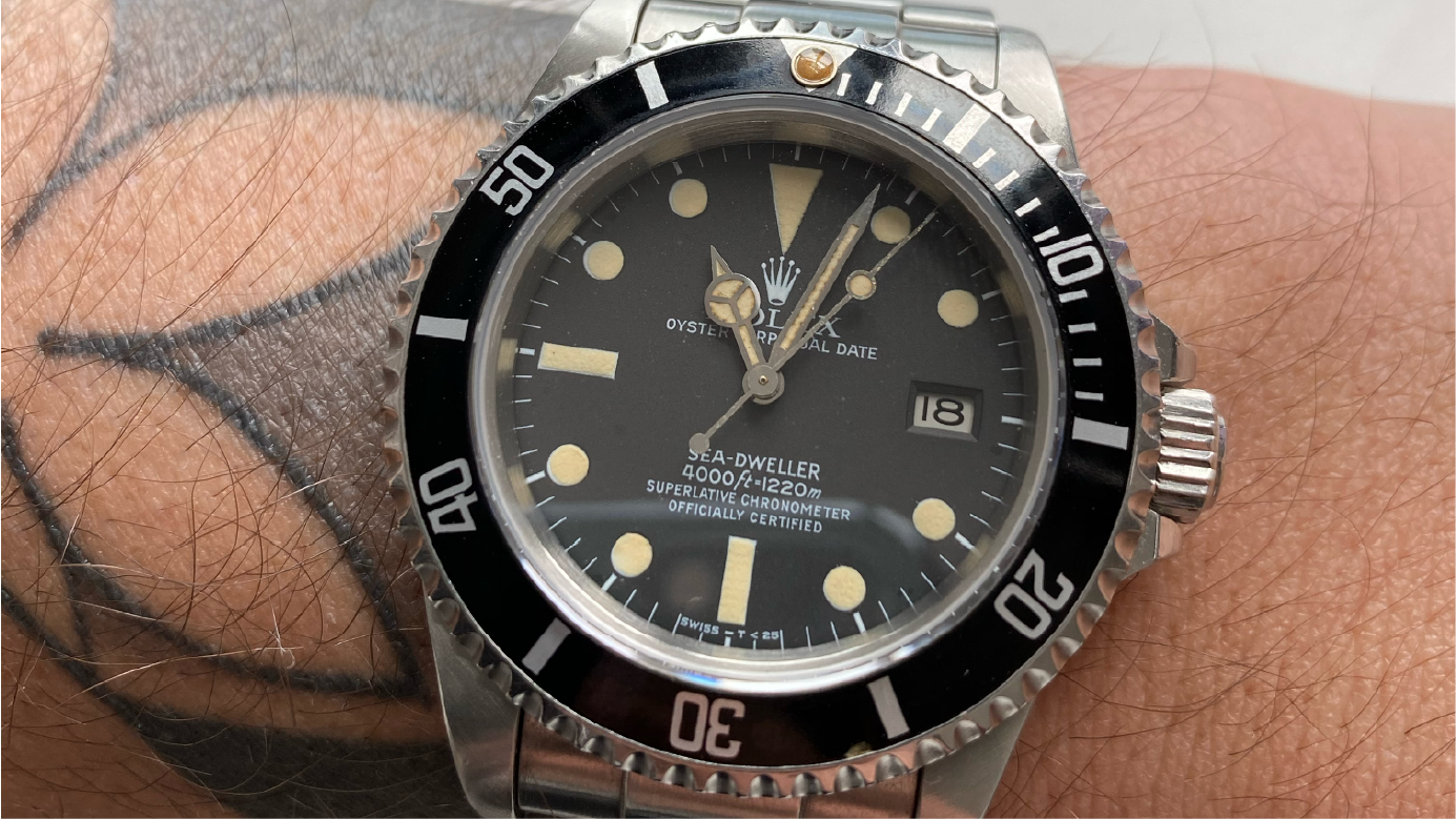 Close up of a Rolex Sea-Dweller "Triple 6" ref. 16660 with a matte dial and cream patina indices and hands.