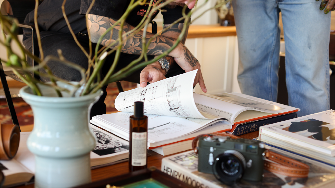 A coffee table full of art, architecture, and design projects. There is a Leica camera in the foreground.