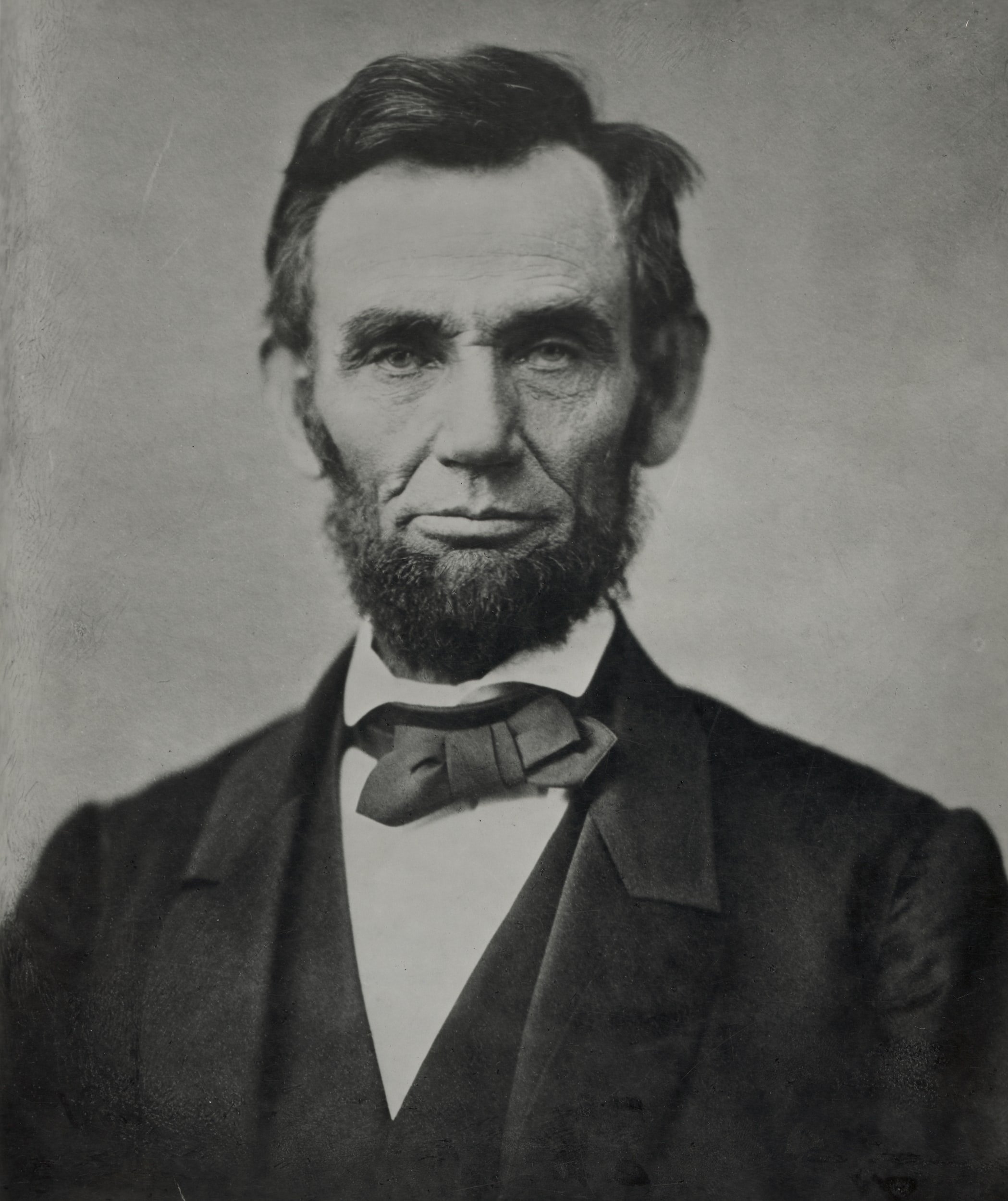 Black and white portrait of a man with a beard wearing a suit and bow tie.