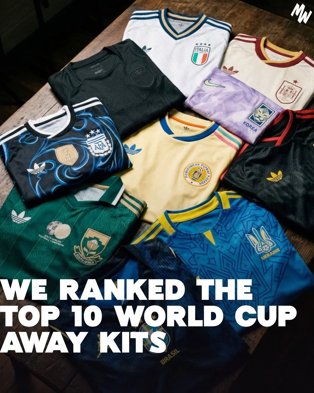 Collection of soccer jerseys from different countries, including Italy, Argentina, South Africa, Ukraine, Spain, Korea, and Brazil, arranged on a wooden surface with the caption "We ranked the top 10 World Cup away kits."