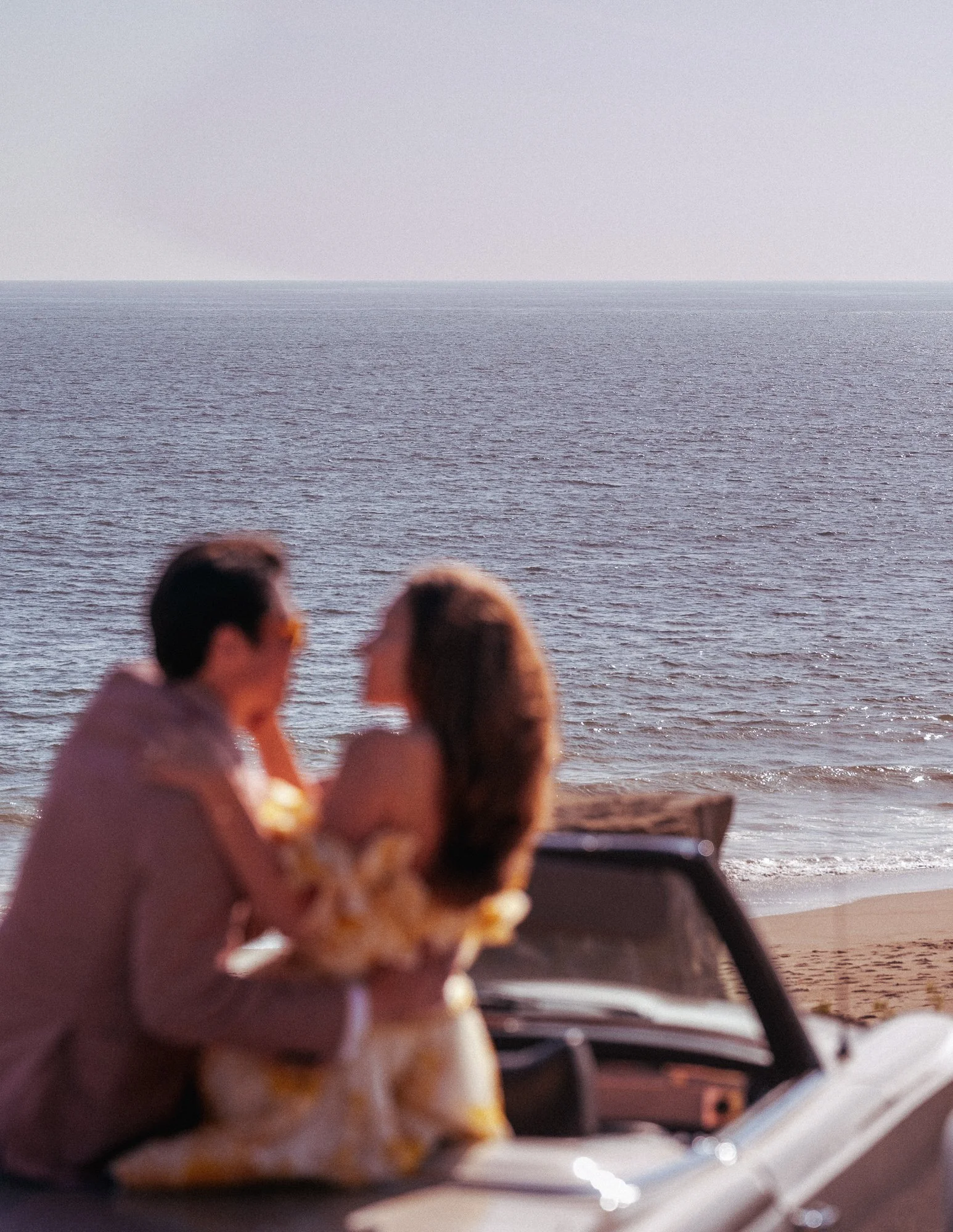 People sitting on a boat near the shoreline, viewing the ocean and horizon, with clouds in the sky.