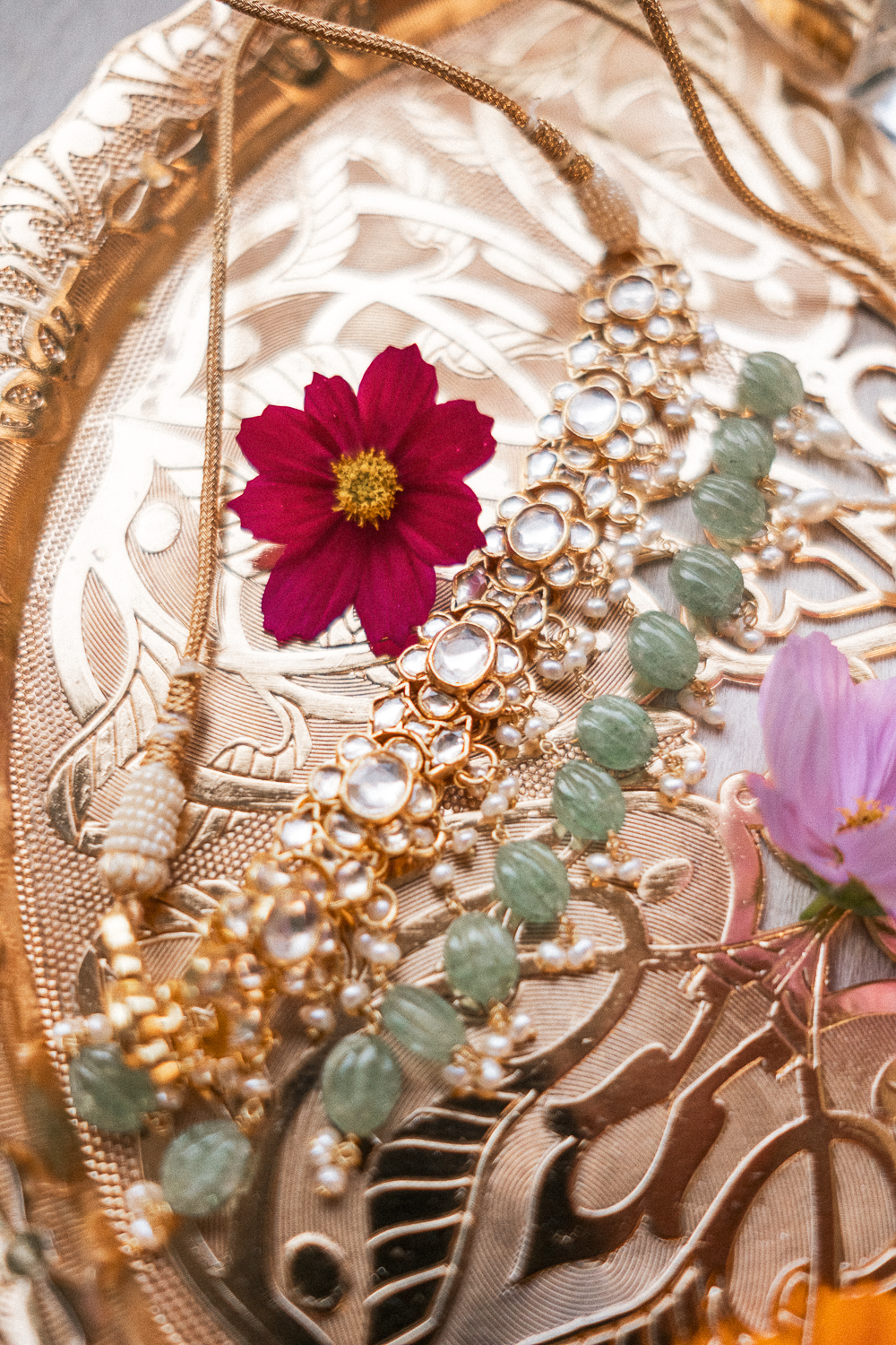 Gold jewelry and floral accessories on a decorative surface.