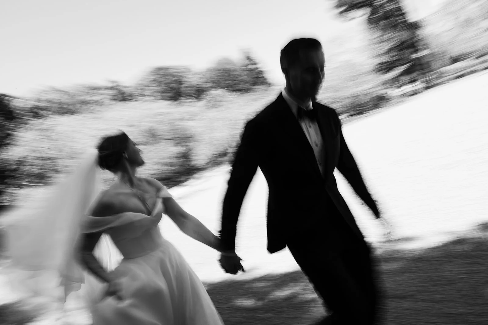 Black-and-white motion blur shows the couple walking briskly hand in hand through a Kyoto hillside.