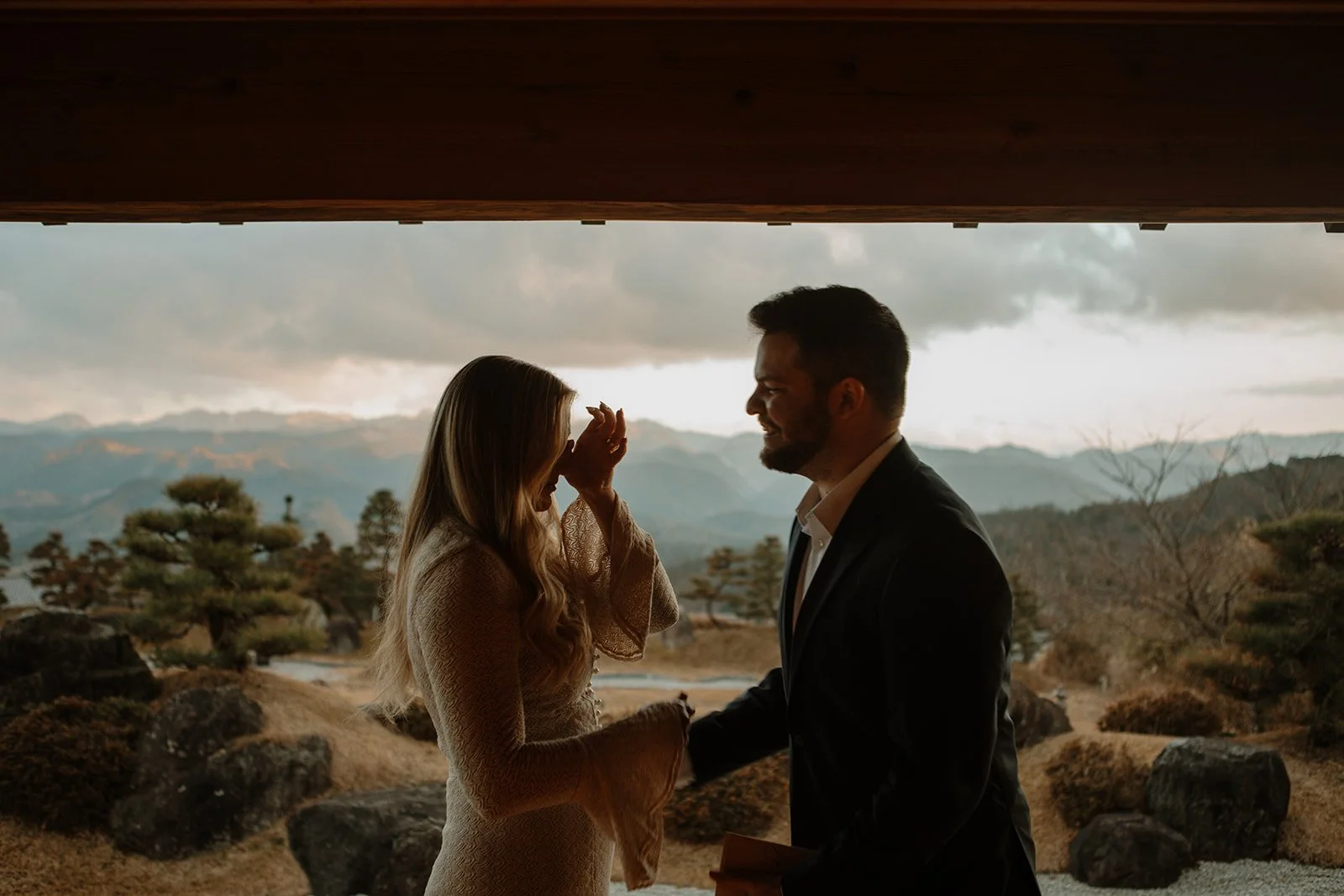 Couple laughs together under a temple veranda overlooking misty mountains in Japan.