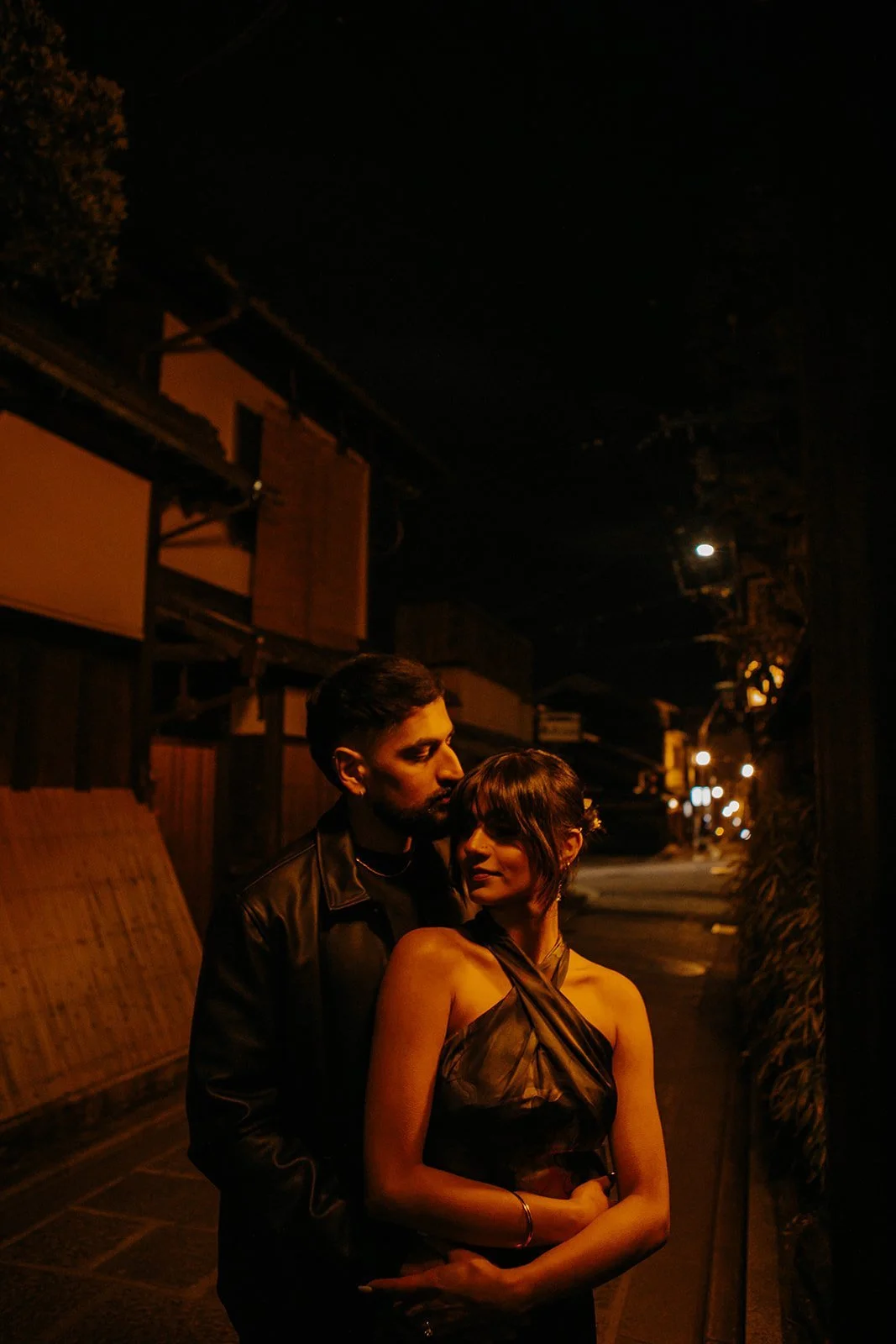 Couple embracing at night in a quiet lantern-lit Gion alley in Kyoto