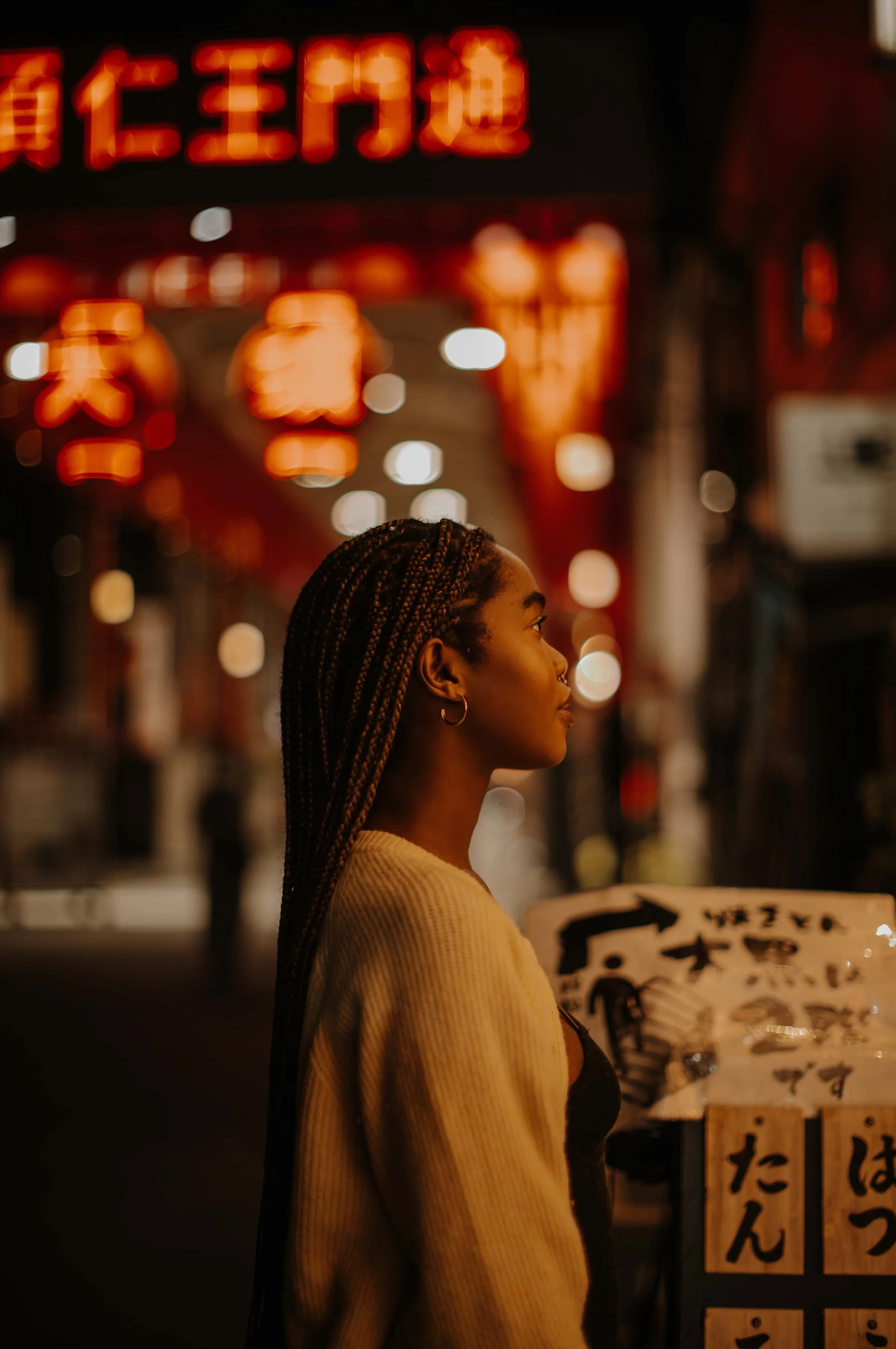 Woman gazing down a lantern-lit yakitori alley in Tokyo, illuminated by warm neon signage.