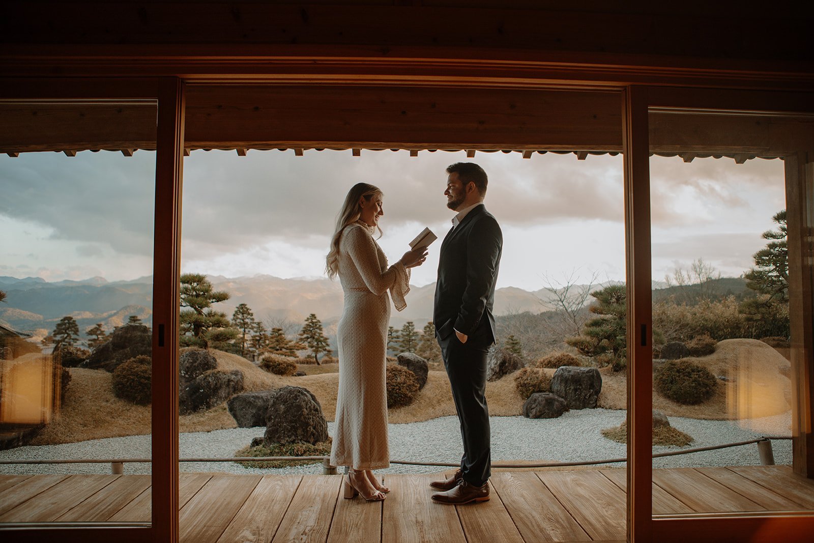 Bride reading her vows to the groom on a wooden veranda overlooking a mountain garden during their Japan elopement ceremony.